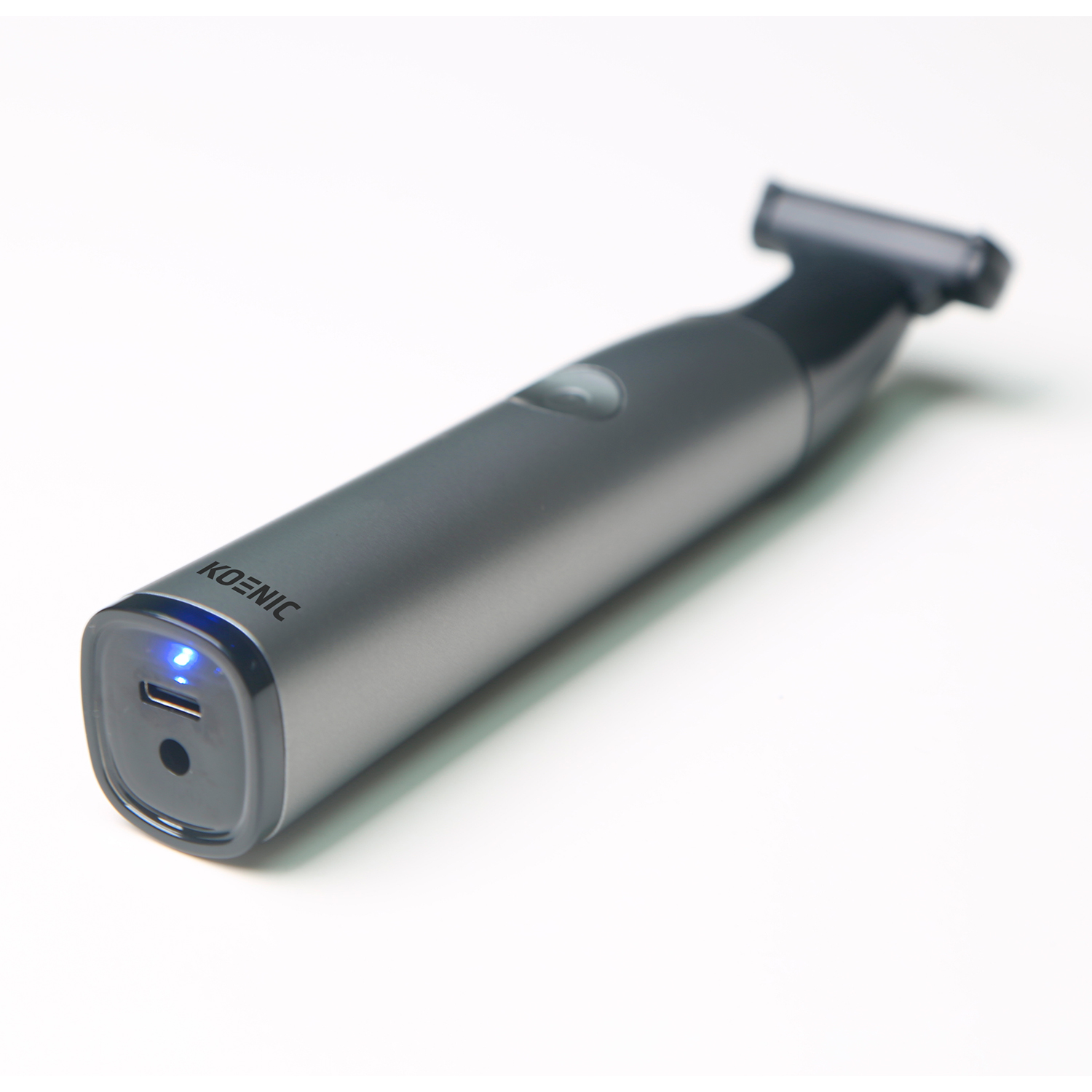 Trimmer Koenic grigio e nero su sfondo bianco. Luce blu vicino alla porta di ricarica.