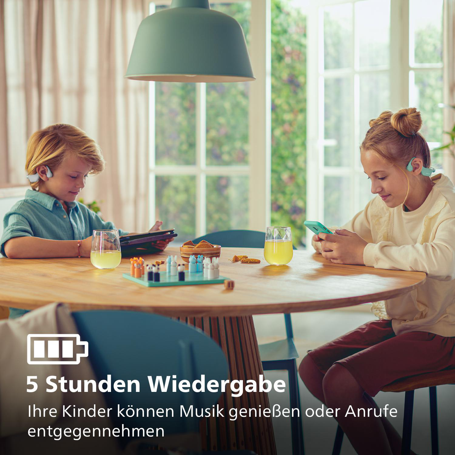 Zwei Kinder mit Kopfhörern benutzen Tablets und Telefone, neben einem Tisch mit Spiel und Getränken.