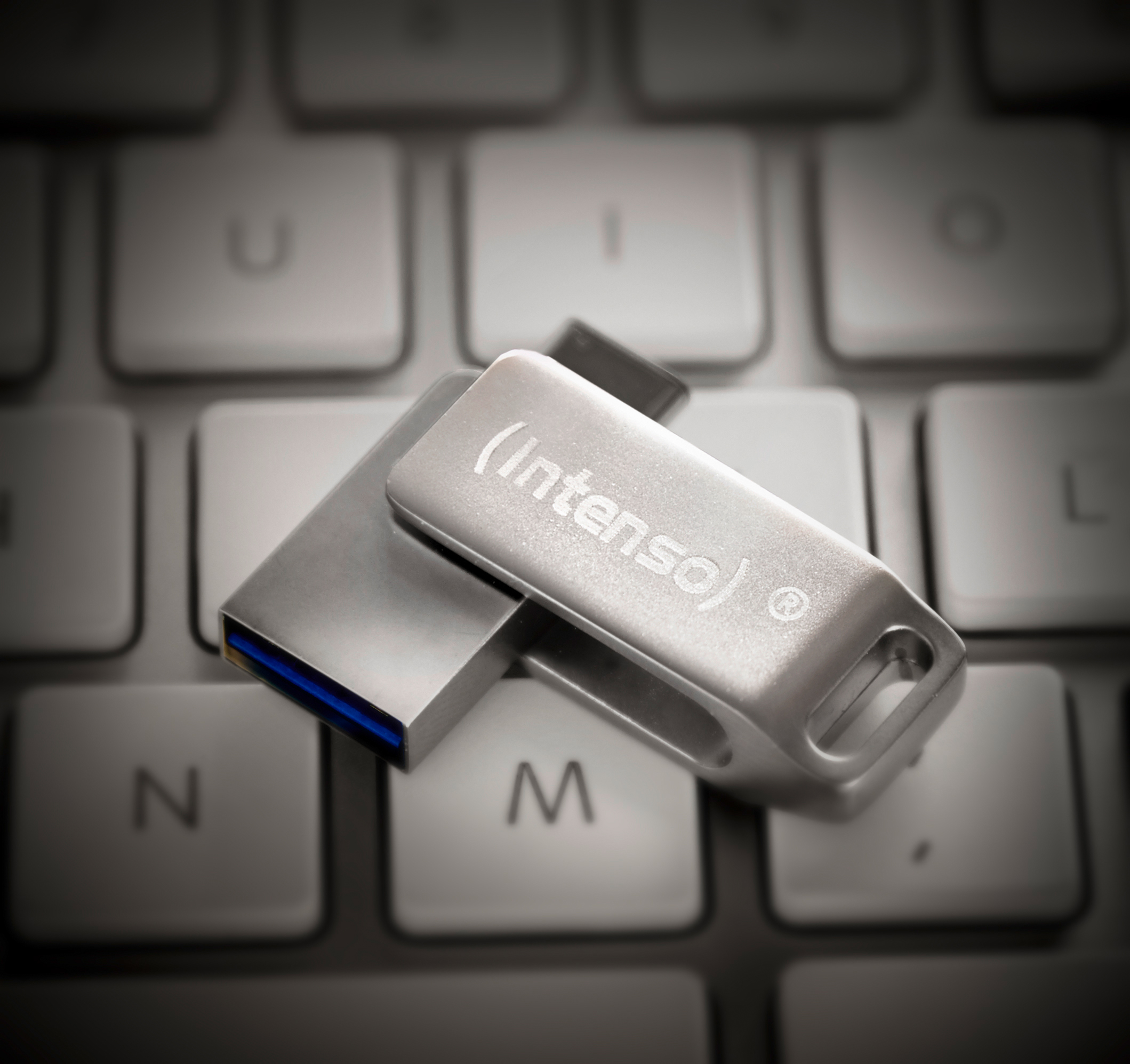 Egy ezüst (Intenso) USB meghajtó egy számítógép billentyűzetén.