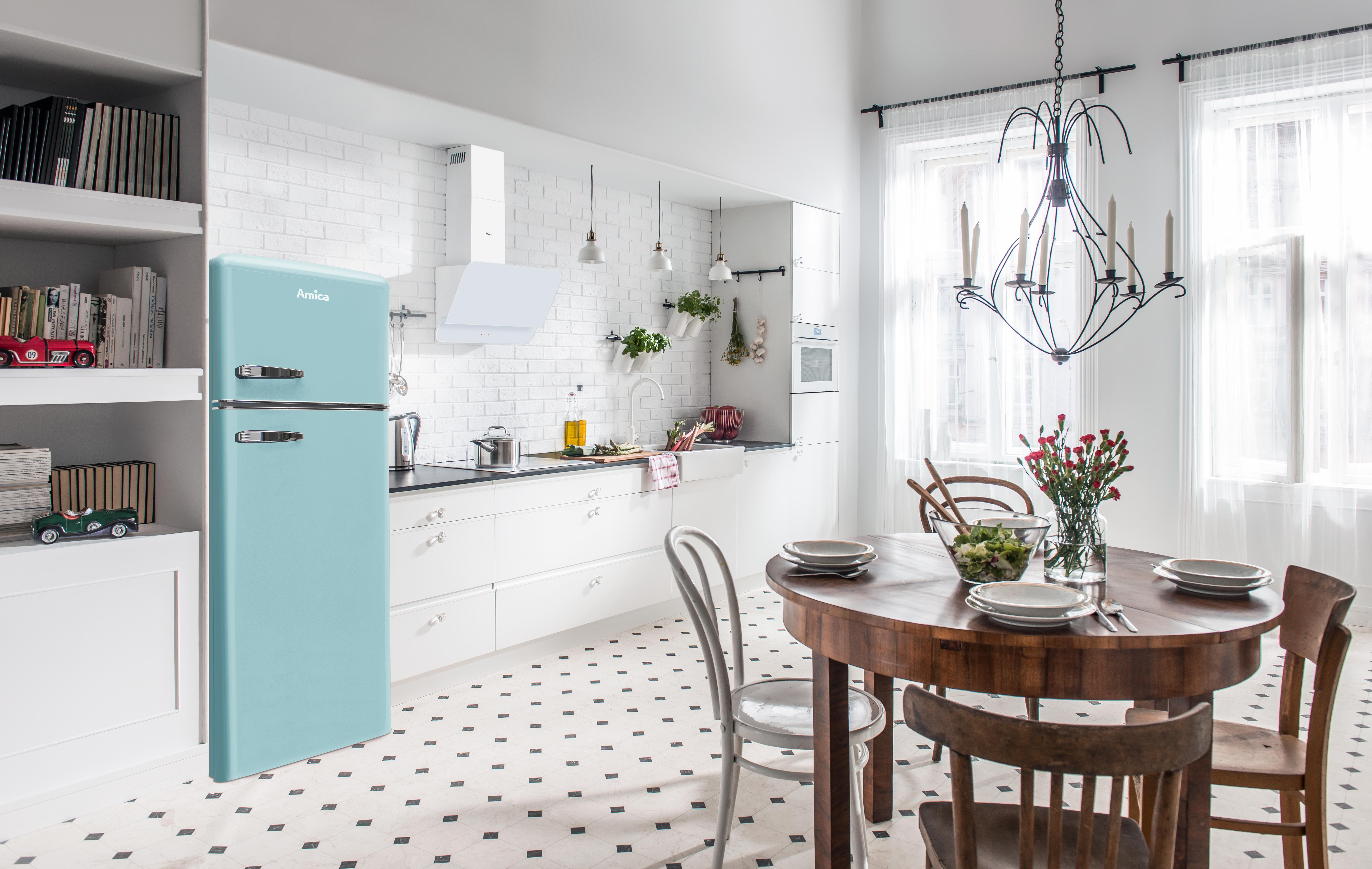 Eine Küche im Retro-Stil mit hellblauem Kühlschrank, rundem Tisch und Kronleuchter.