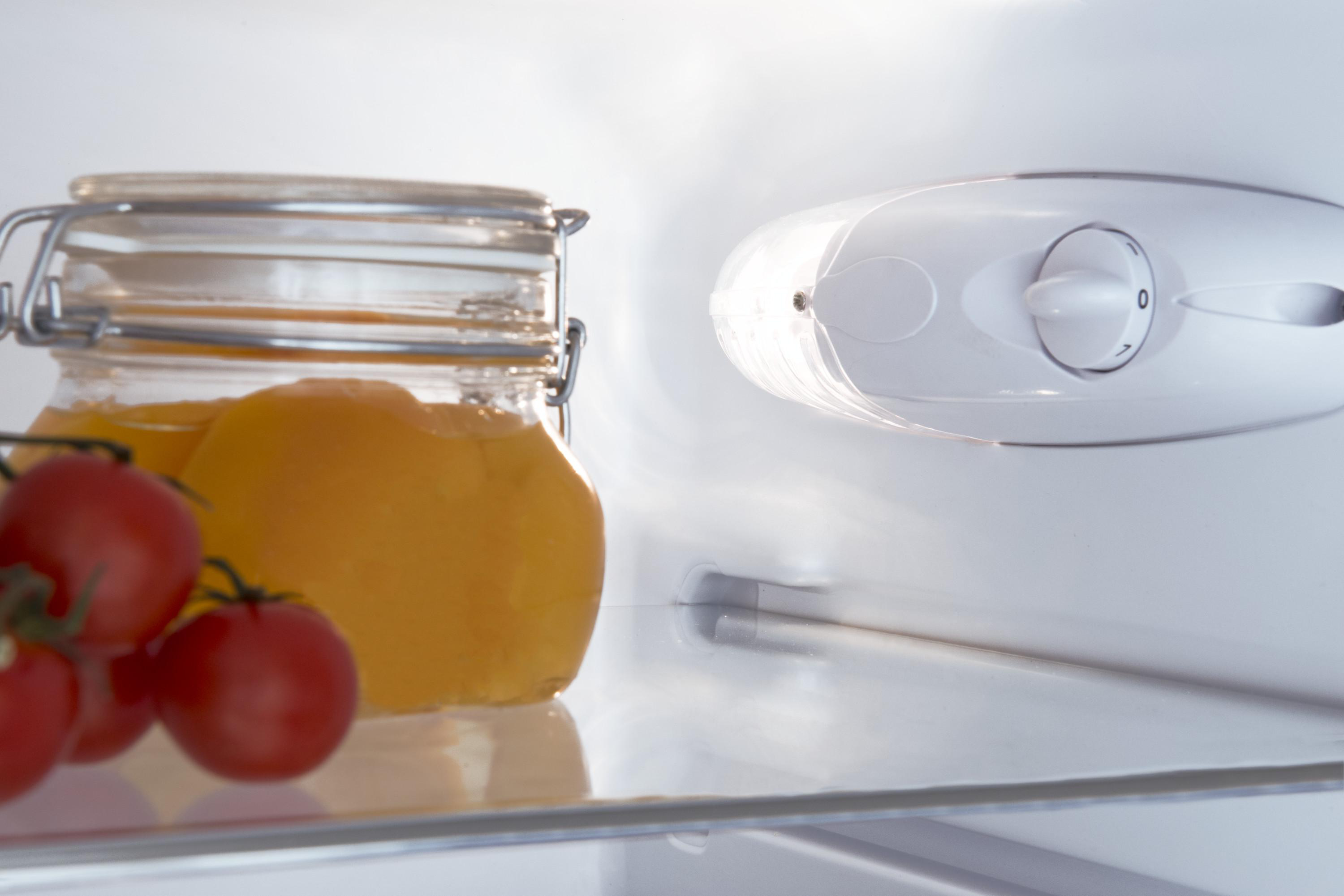 In einem Kühlschrank. Gläser mit Orangenmarmelade, Tomaten und eine Leuchte.