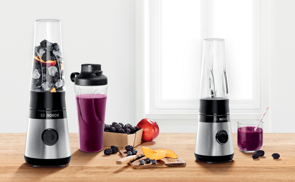 Blenderlar ve malzemelerle bir mutfak sahnesi. İki blender, biri smoothie, diğeri meyvelerle dolu.