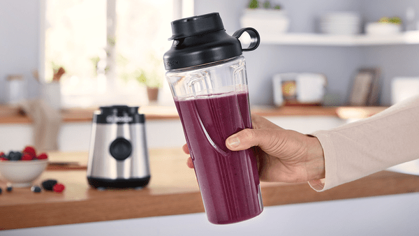 Paslanmaz çelik bir kaseye sahip gümüş bir KitchenAid mikser. Malzemeler ve kavanozlar görünür.