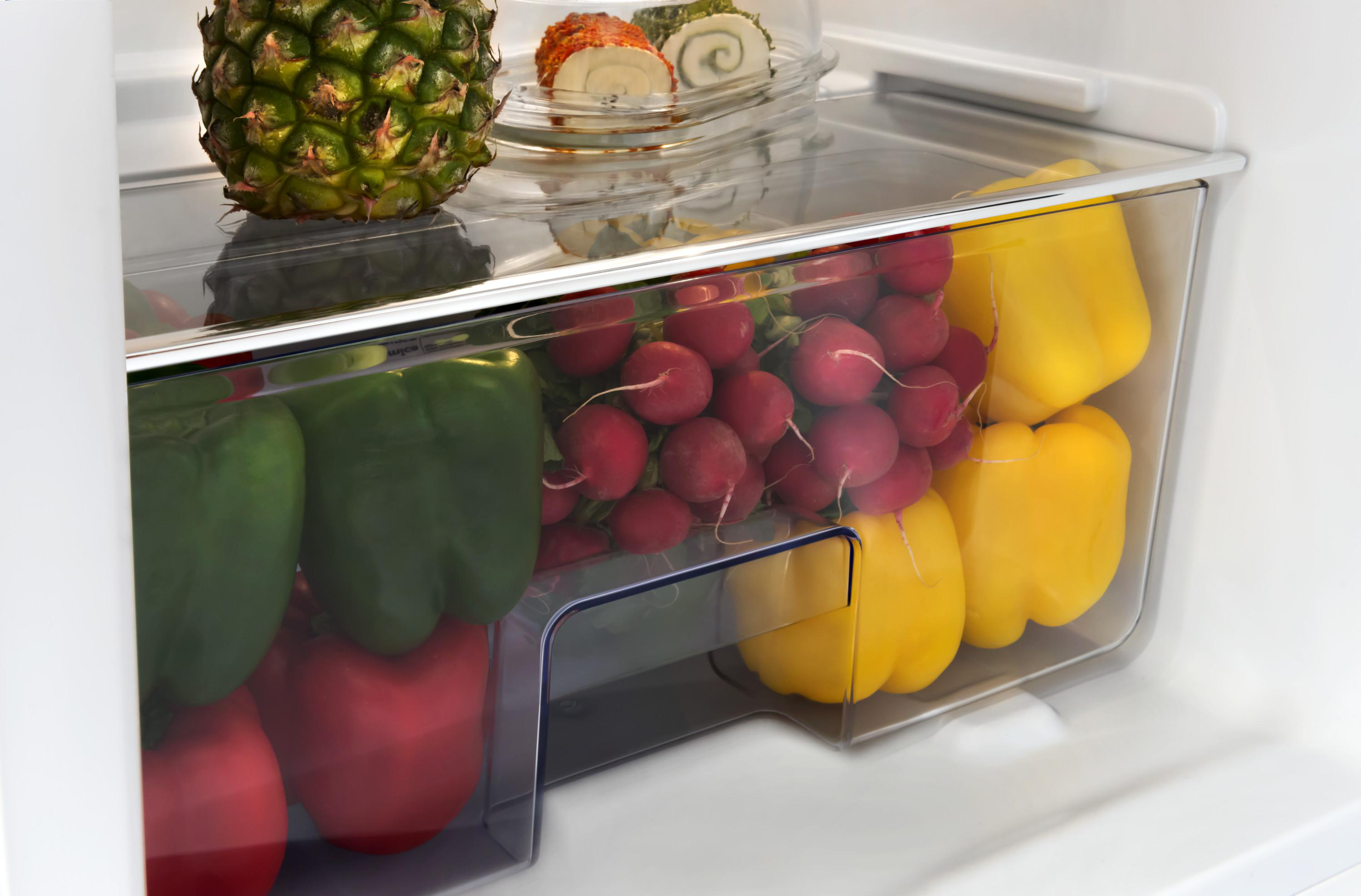Kühlschrankinnenraum mit Gemüse: Paprika, Radieschen und Ananas.