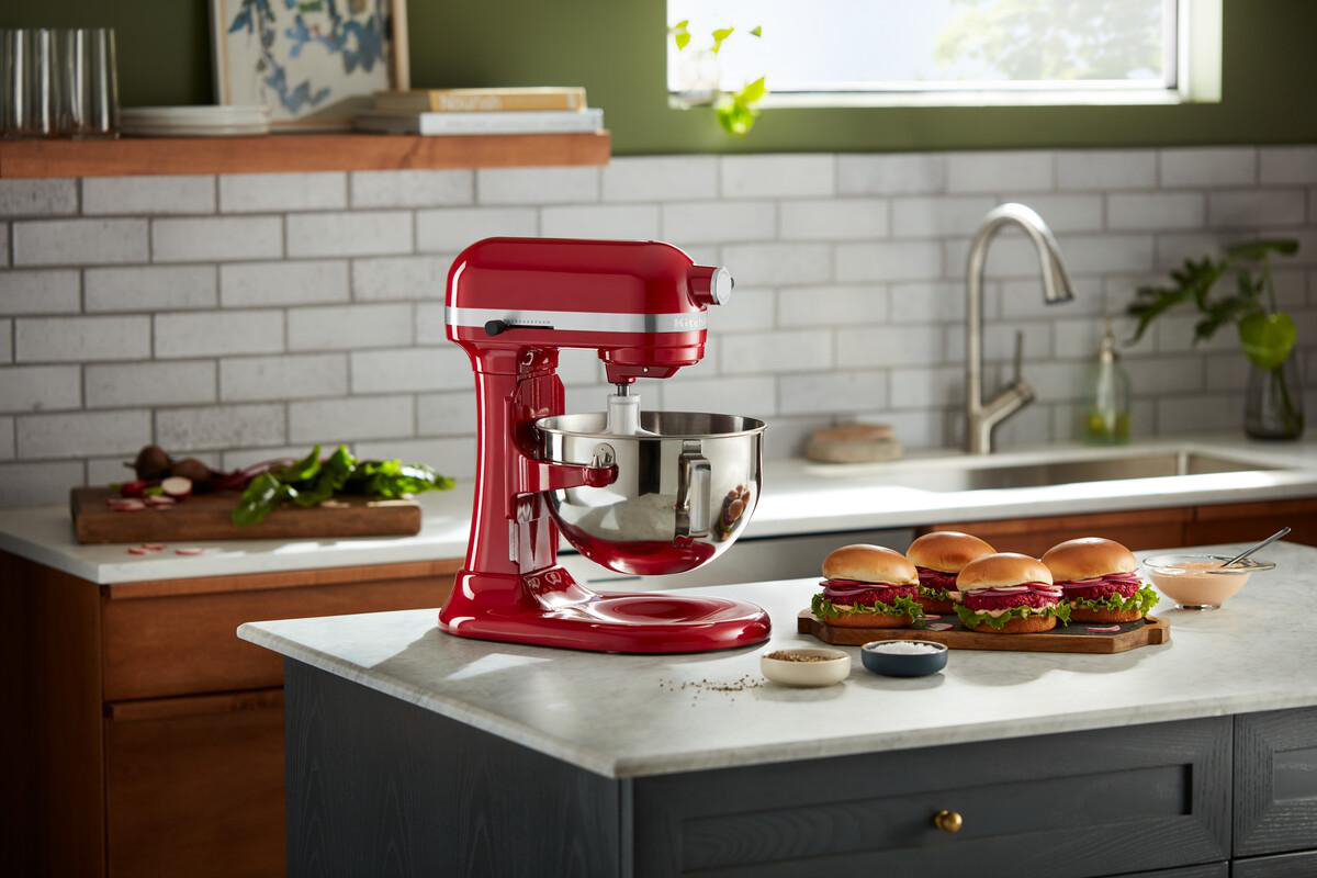 Roter KitchenAid-Mixer auf einer Küchentheke mit Burgern und Zutaten.