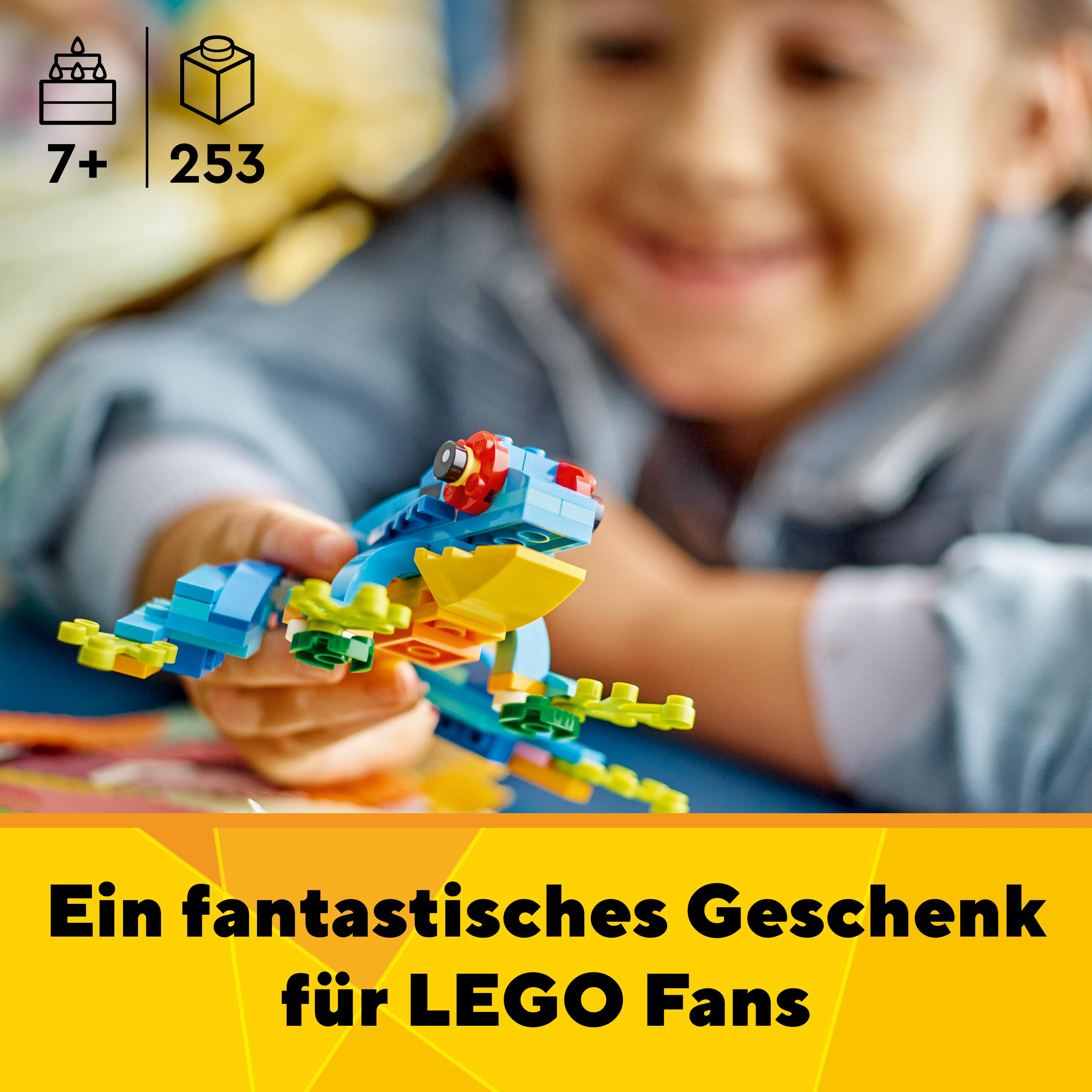 Ein Mädchen lächelt und hält ein blau-gelbes Lego-Froschmodell.