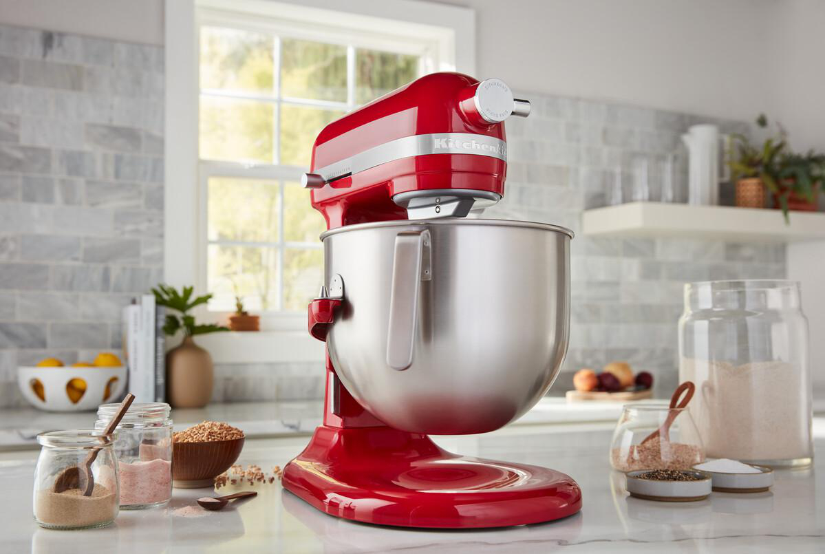 Roter KitchenAid Mixer auf einer Küchentheke, mit Gläsern und Zutaten.