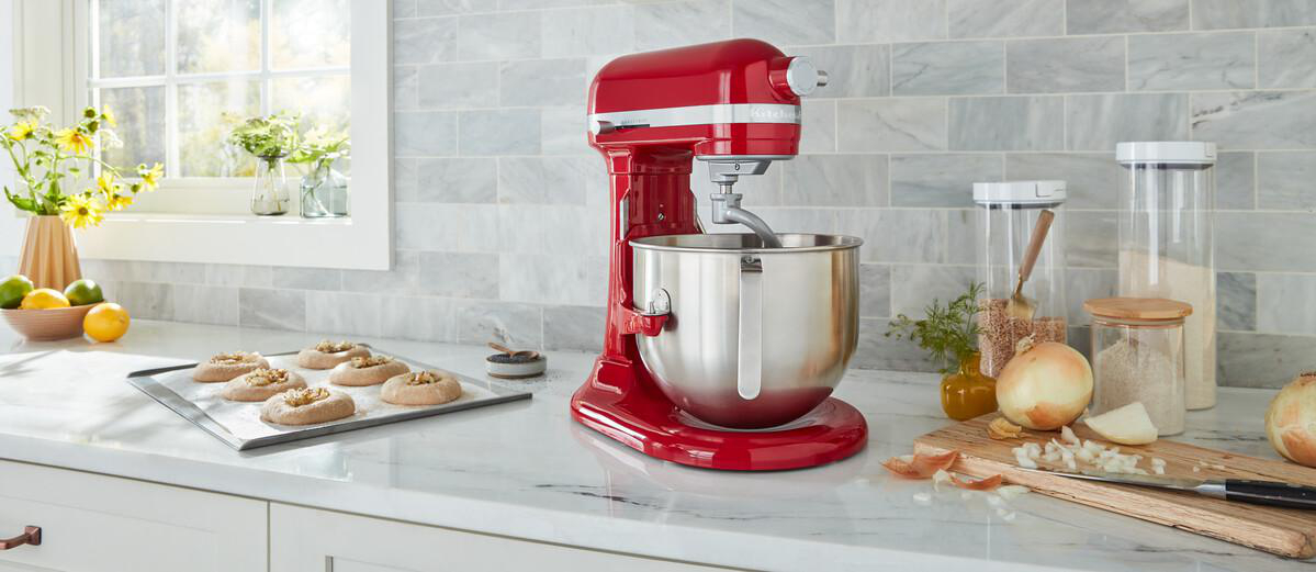 Ein roter KitchenAid-Küchenmixer mit einer Schüssel und Zutaten auf einer Küchenarbeitsplatte.