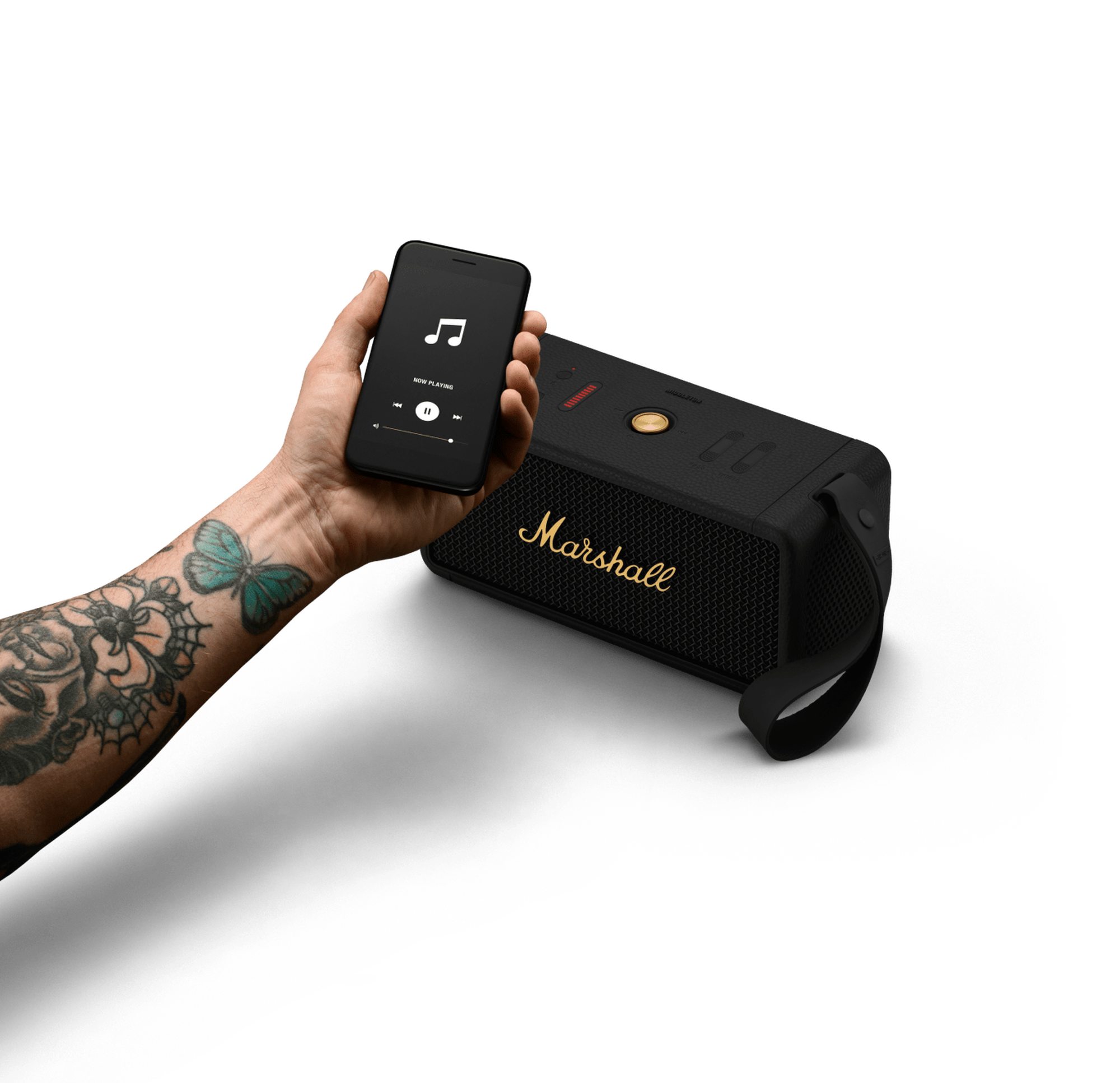 Person mit Tattoo hält Handy mit Musik abspielen neben schwarzem Marshall-Lautsprecher.