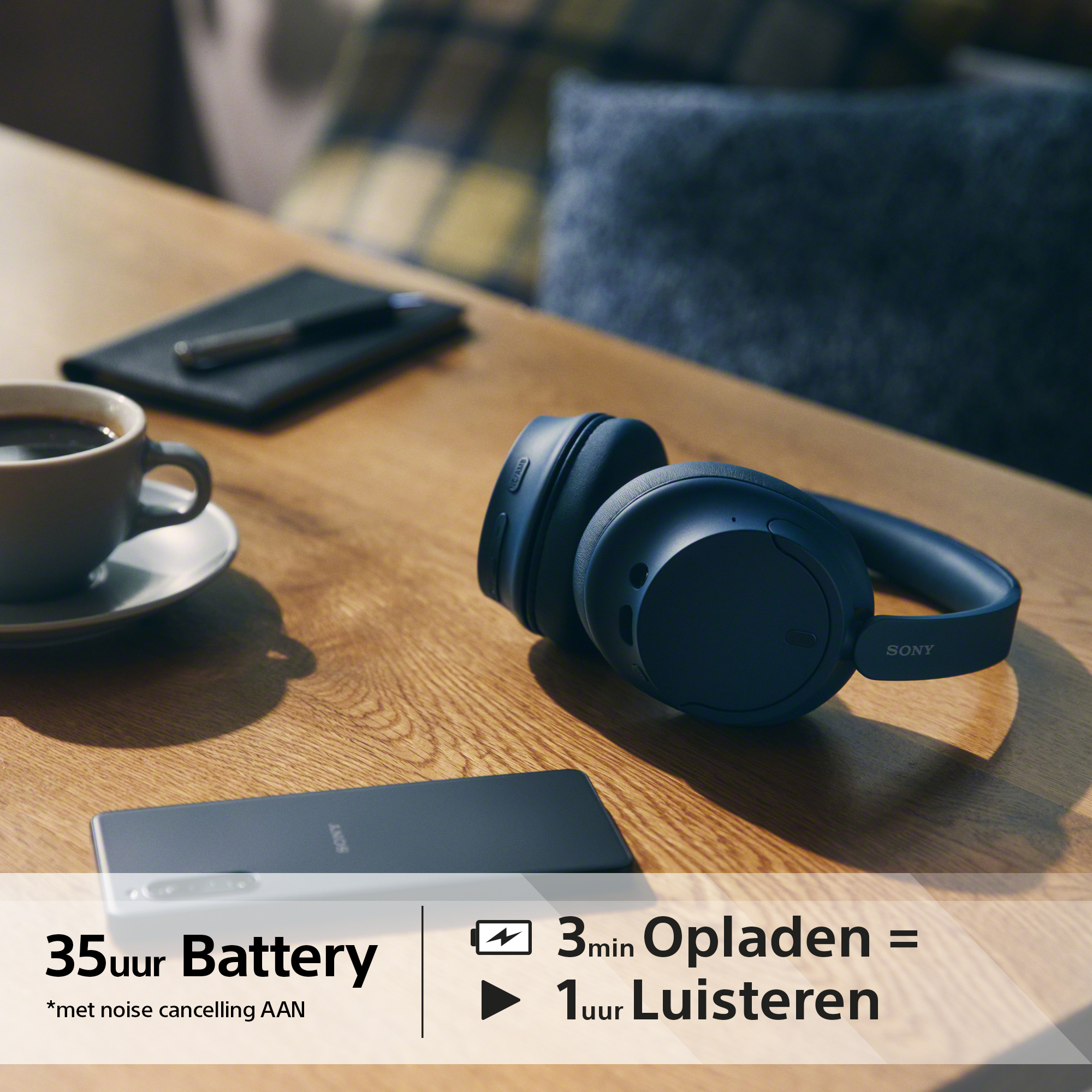 Casque sur table en bois, téléphone, café et texte sur l'autonomie de la batterie sont visibles.