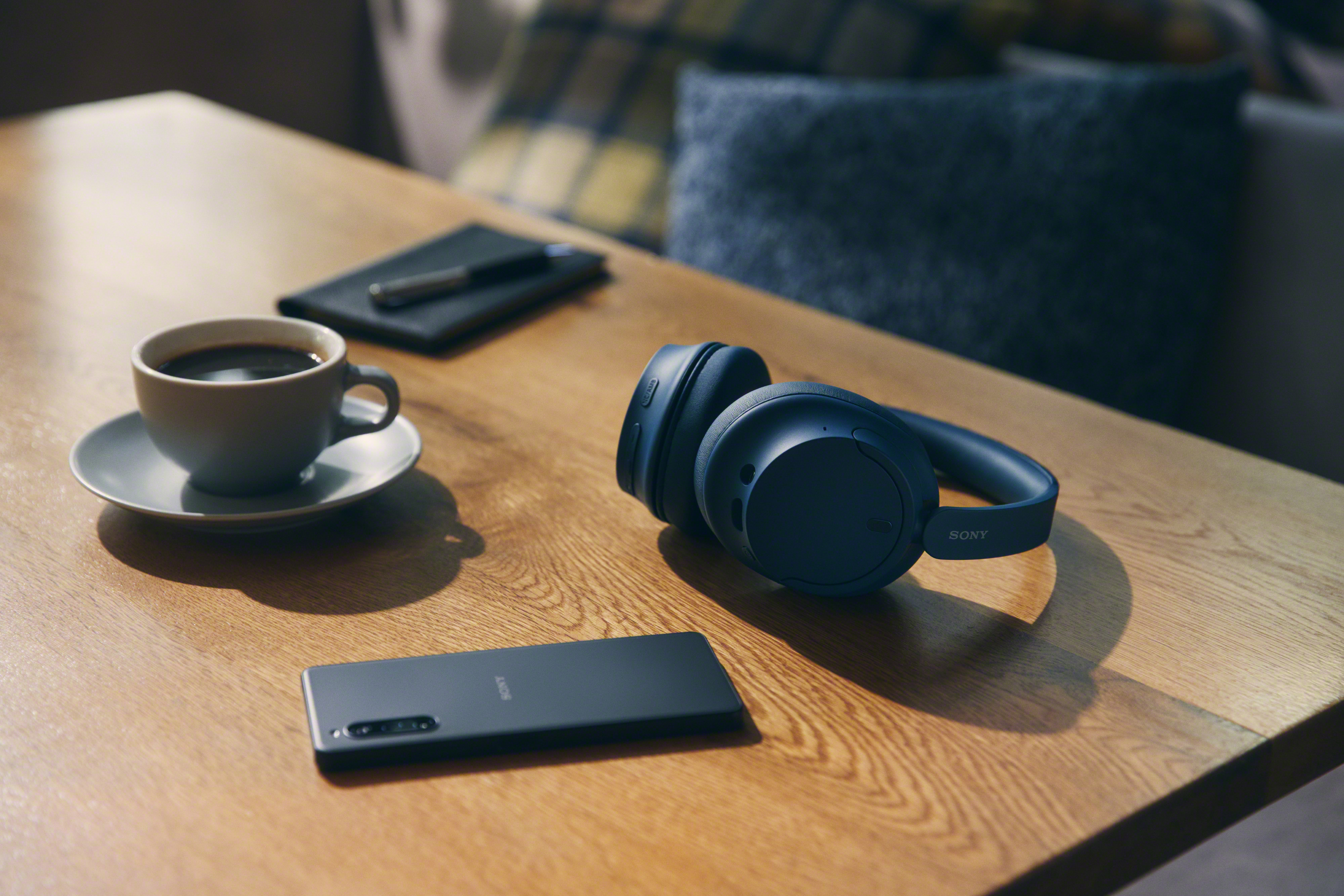 Casque, téléphone, bloc-notes et café sur une table en bois.