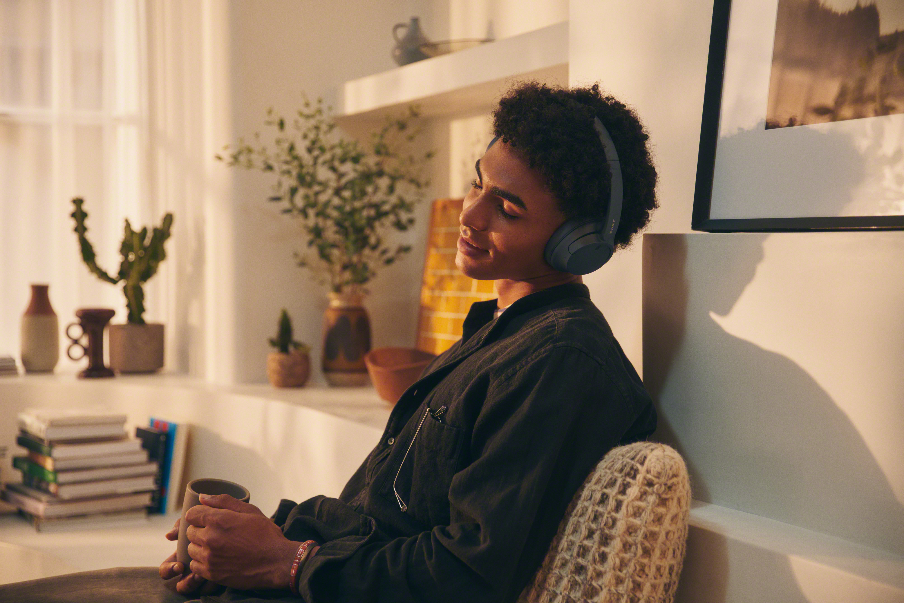 Personne portant un casque gris, assise détendue, tenant une tasse à l'intérieur.