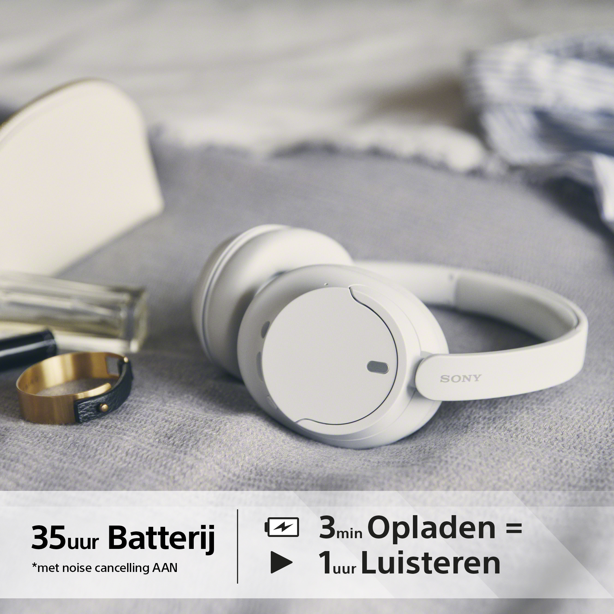 Casque blanc, bague et parfum sur un lit.