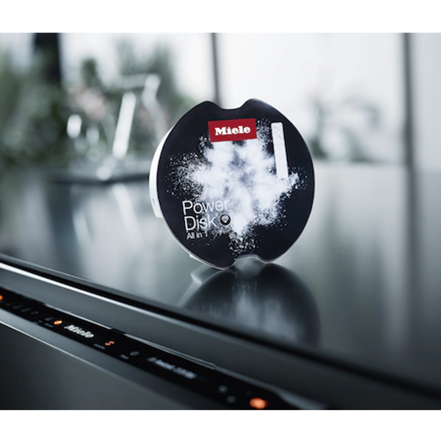 Detersivo Miele PowerDisk su una superficie in acciaio inox. È visibile polvere bianca.