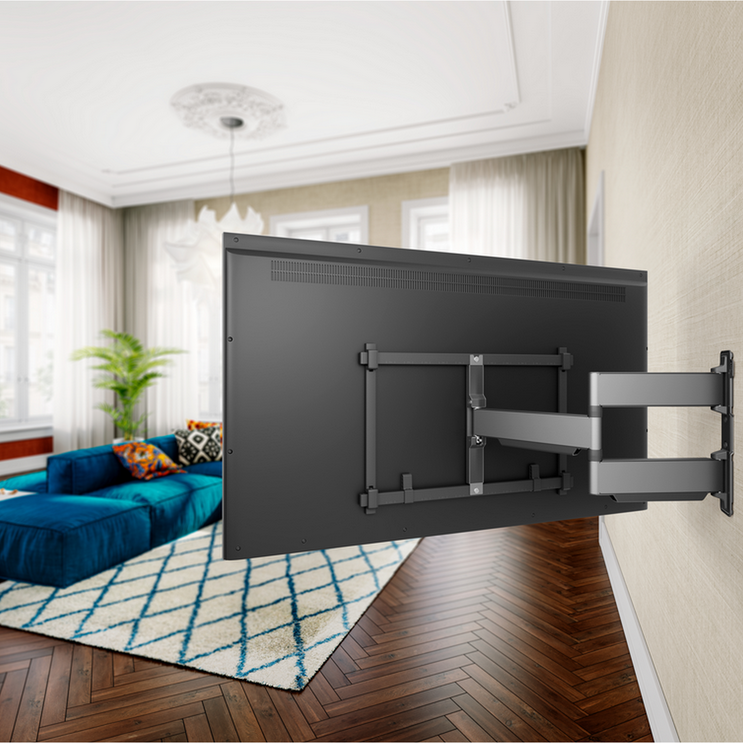 A large TV mounted on a wall with a grey bracket. Blue sofa and patterned rug in the background.