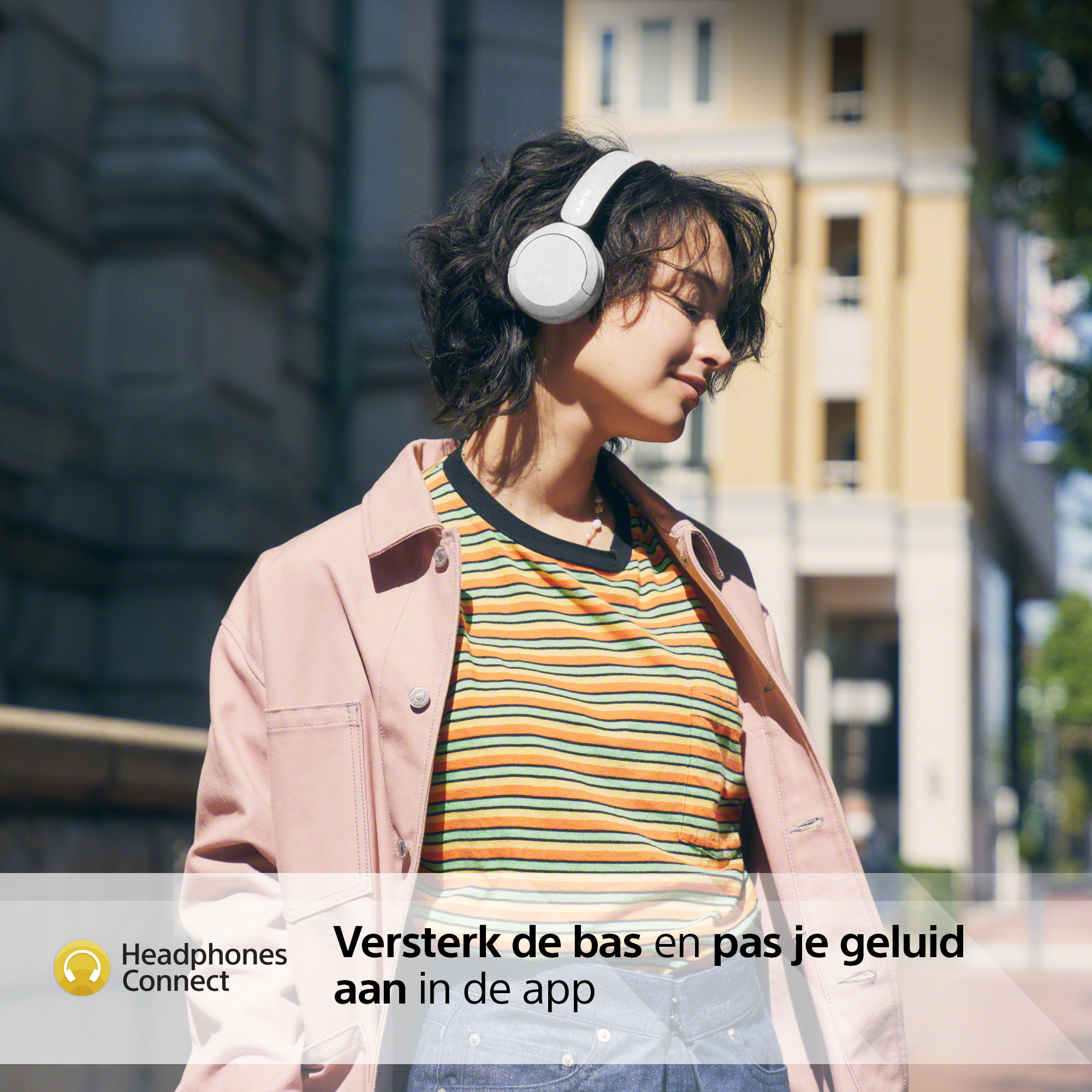Une femme portant un casque blanc. Elle est dehors. Bâtiments en arrière-plan.