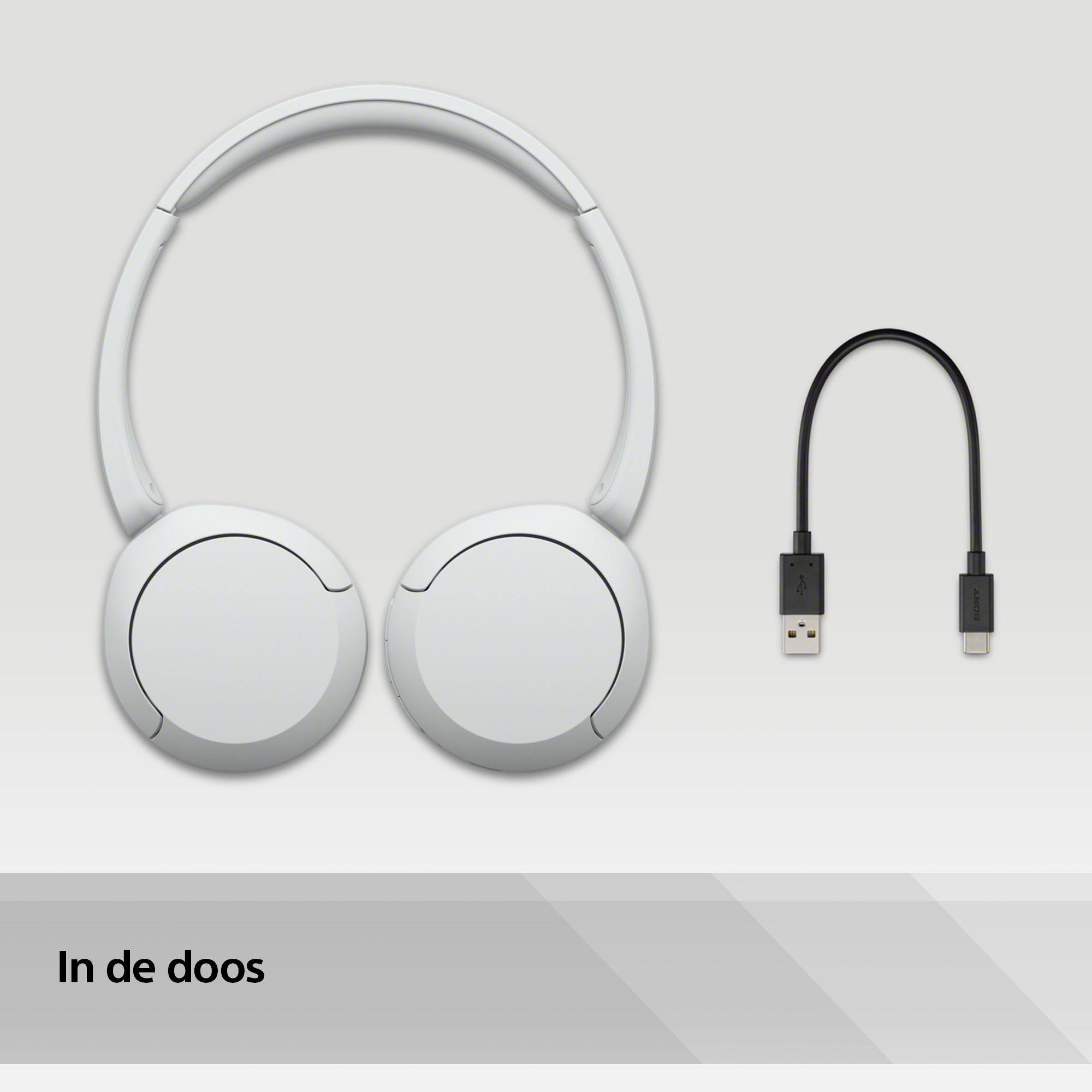 Un casque blanc et un câble de chargement noir sur un fond gris clair.