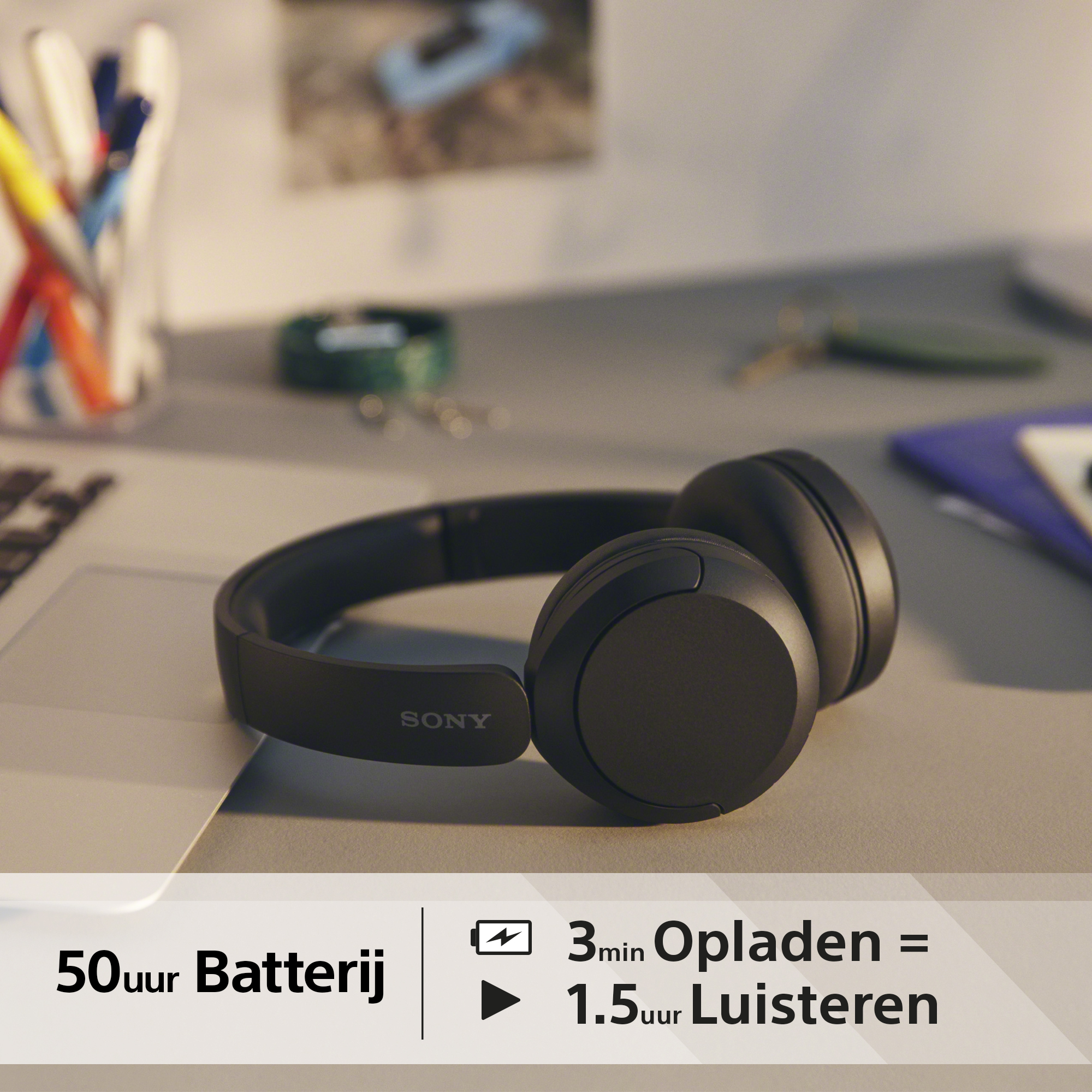 Black Sony headphones on a desk. Info: 50 hours battery, 3 min charge = 1.5 hours listen time.