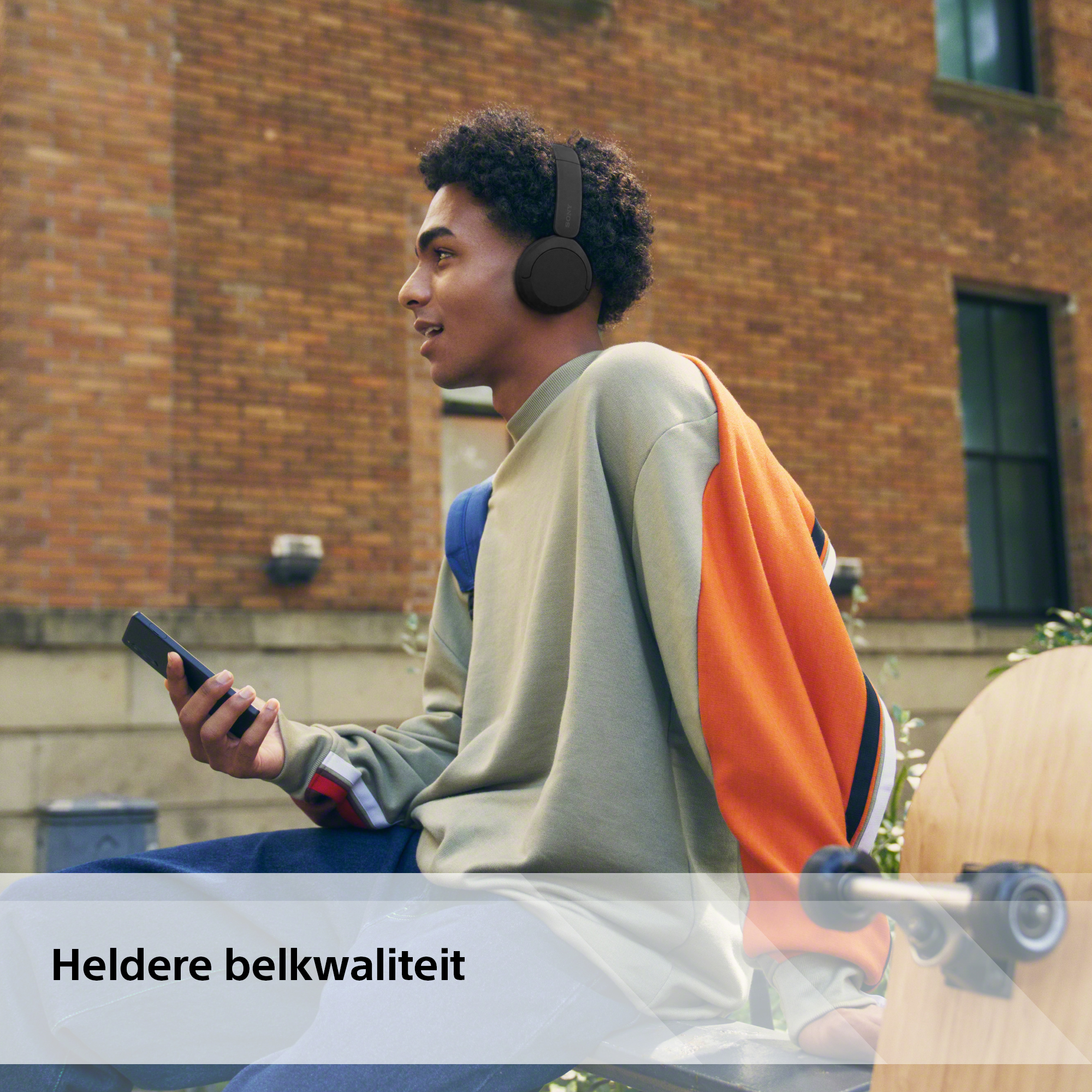 Young man with black headphones and phone. Brick wall background. Text: 'Clear call quality'.