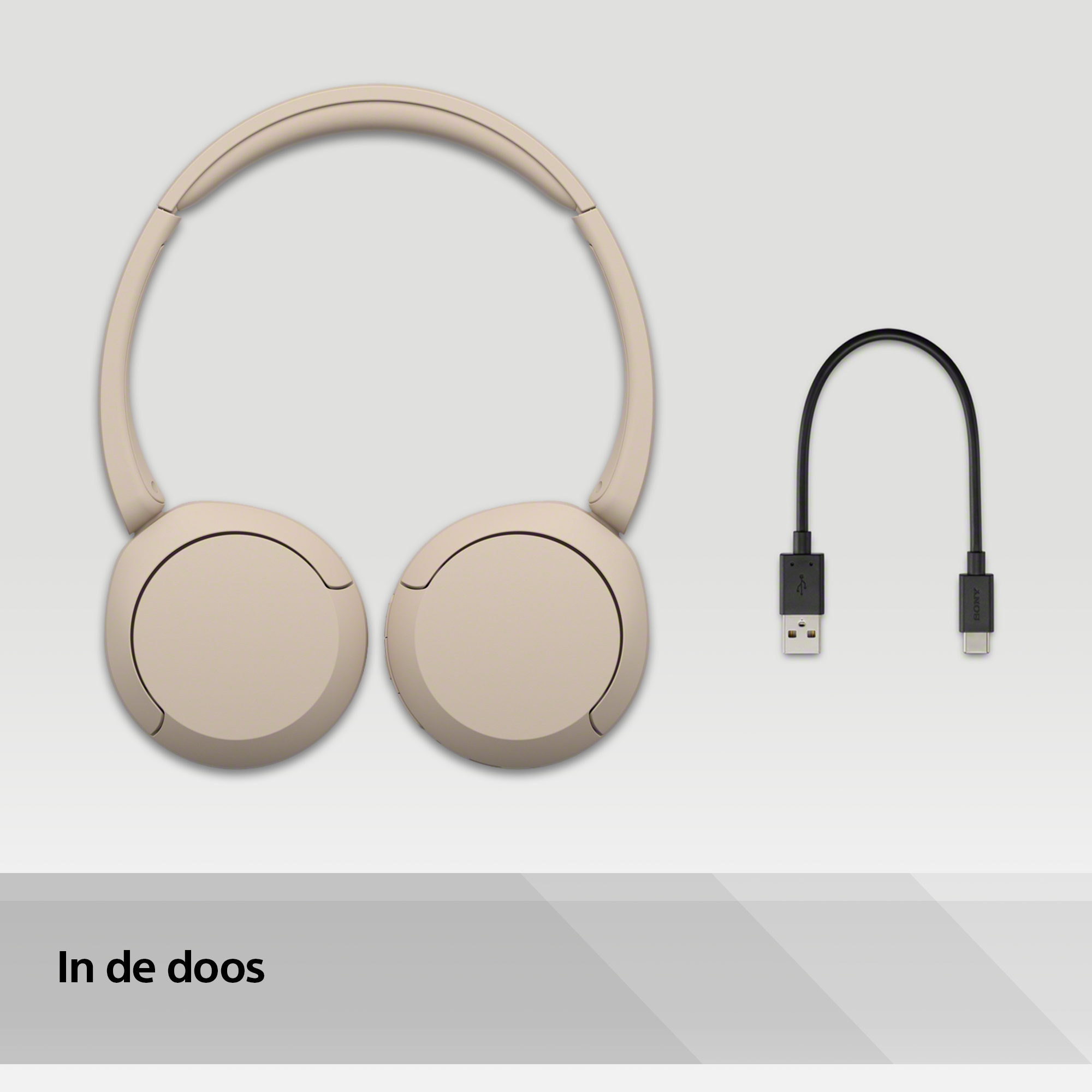 Beige koptelefoon en een zwarte USB-C-kabel op een lichtgrijs oppervlak. Tekst: 'In de doos'.