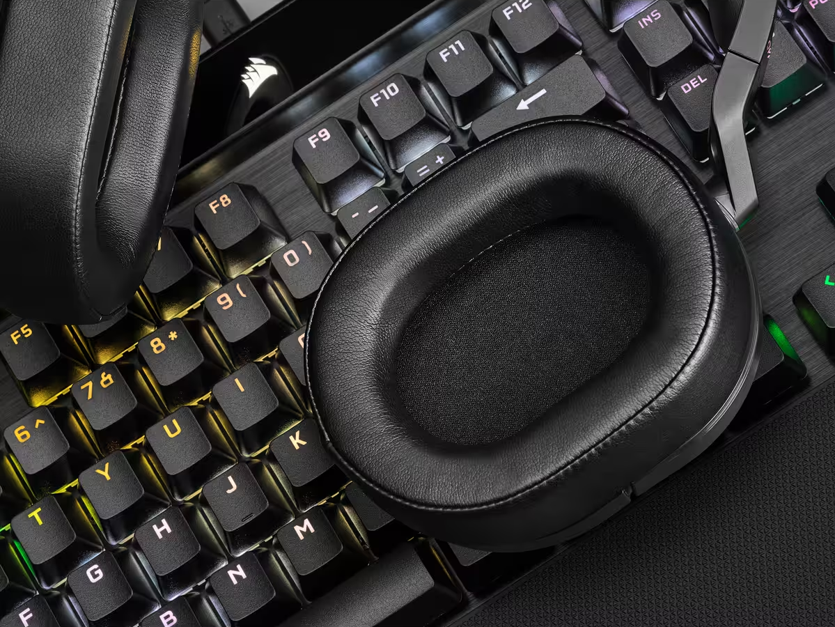 Casque noir posé sur un clavier. Clavier noir avec touches éclairées. Gros plan.