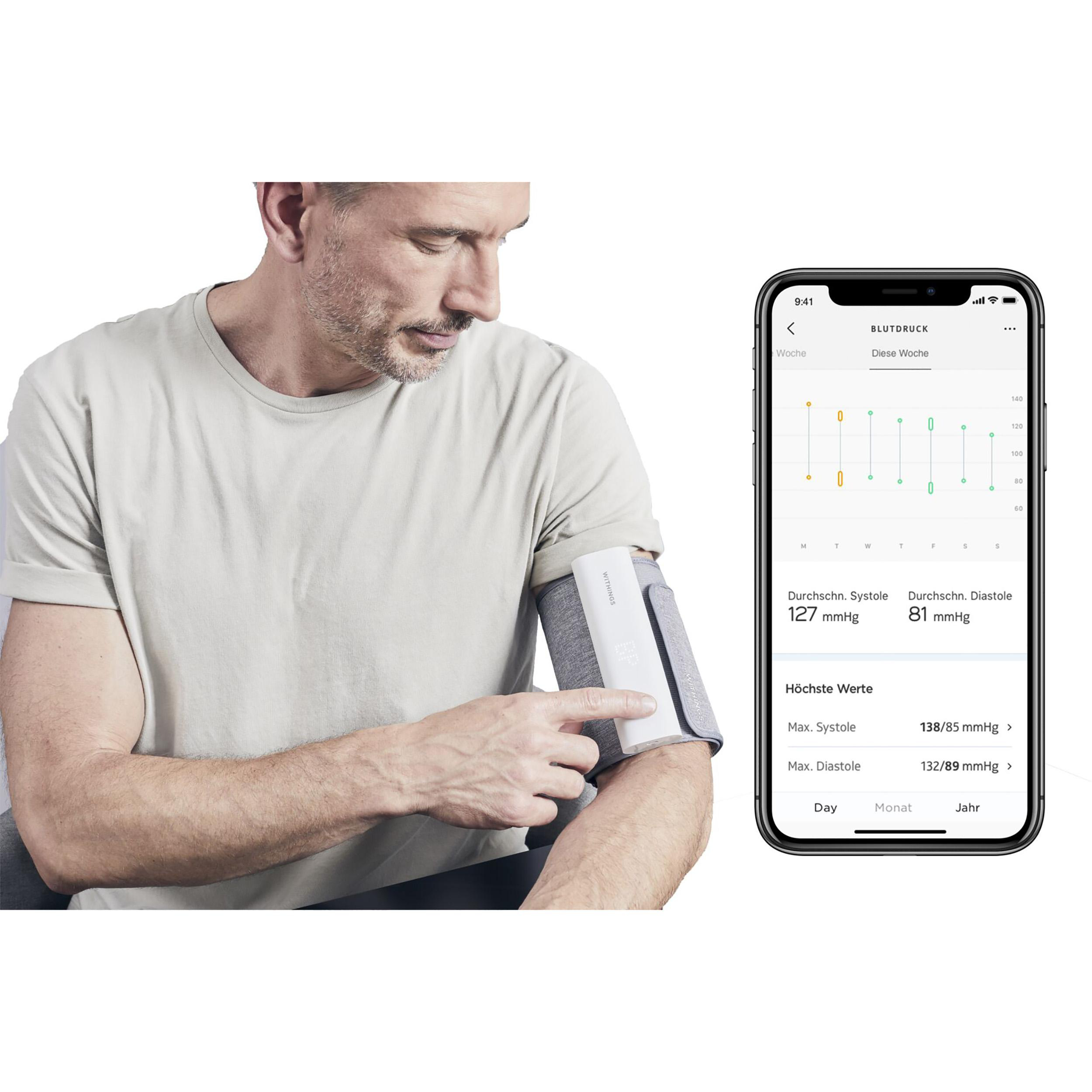 Mann misst Blutdruck mit Gerät am Arm. Telefon zeigt Messwerte und Diagramm.