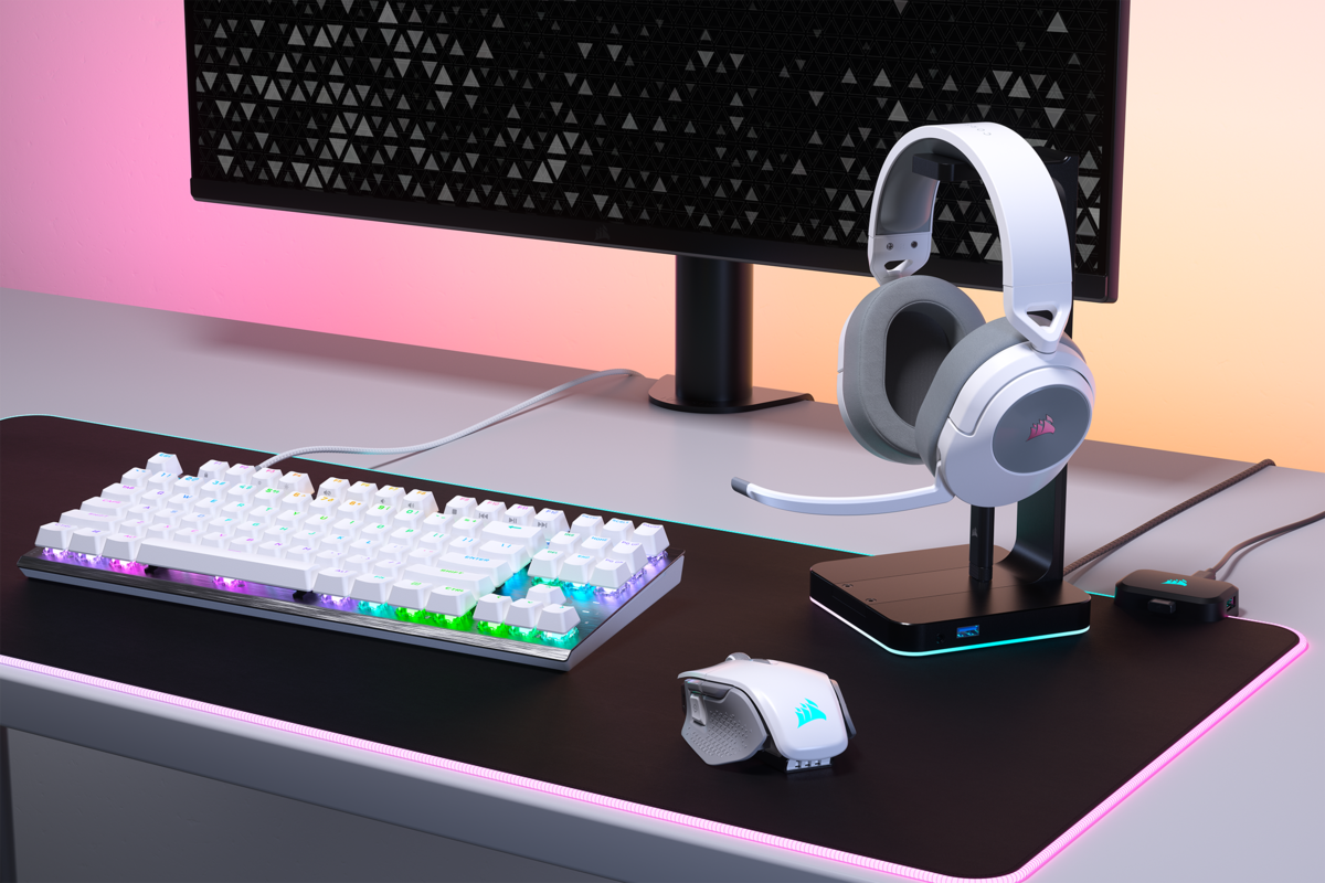 Ein Gaming-Setup mit weißer Tastatur, Maus und Headset. Rosa und orangefarbene Beleuchtung.