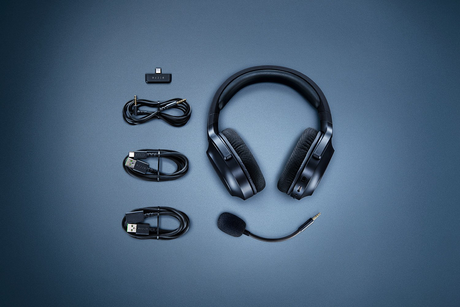 Casque noir, câbles et adaptateur USB sur une surface bleue.