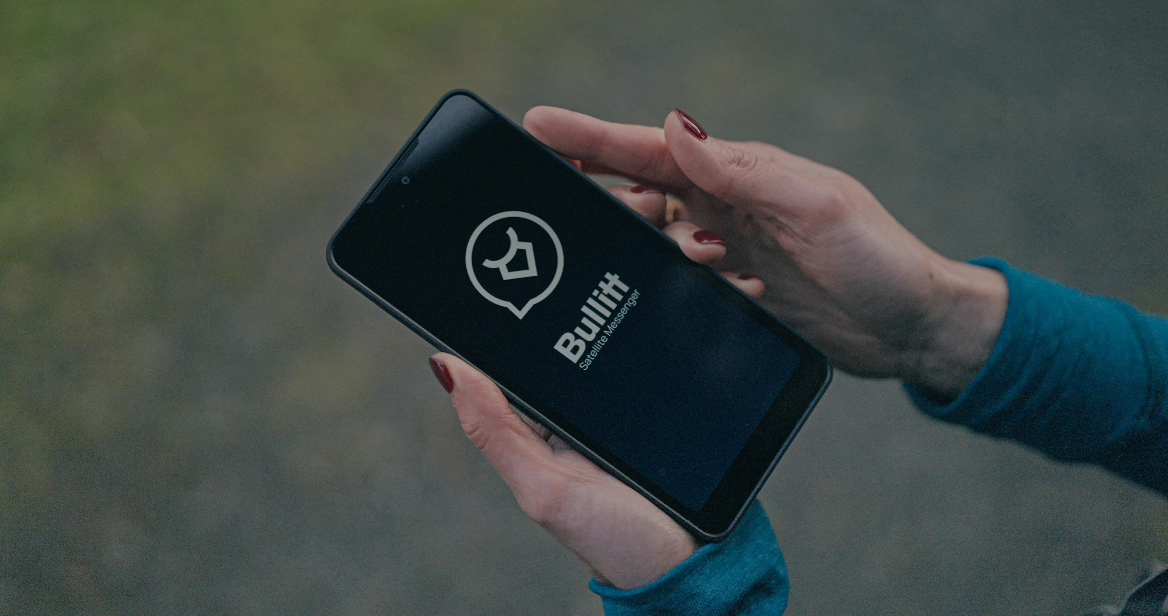 Hände einer Person, die ein Smartphone mit dem Logo von Bullitt Safe Messenger halten.