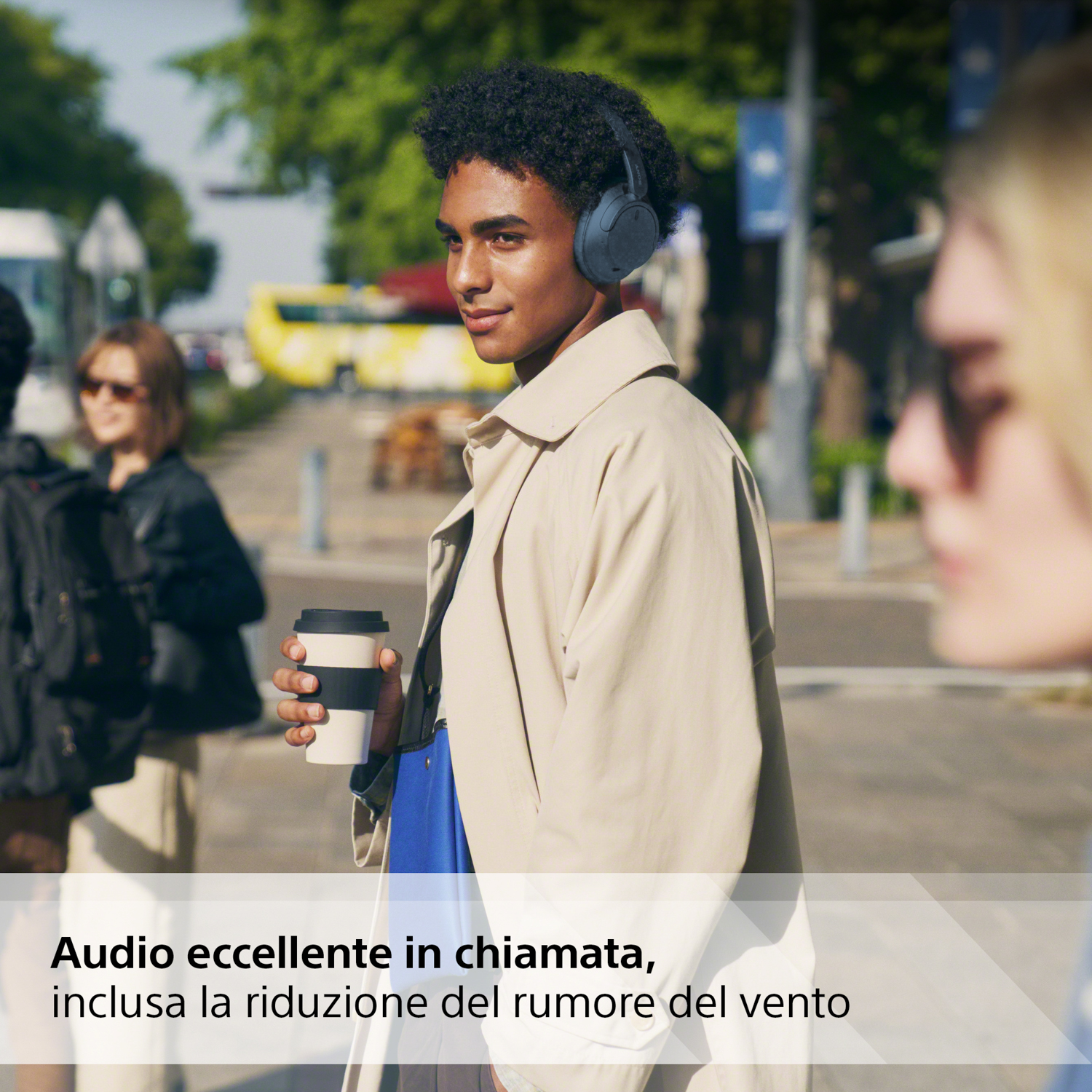 Un uomo con cuffie blu. Tiene in mano una tazza di caffè. Testo: Audio eccellente in chiamata.