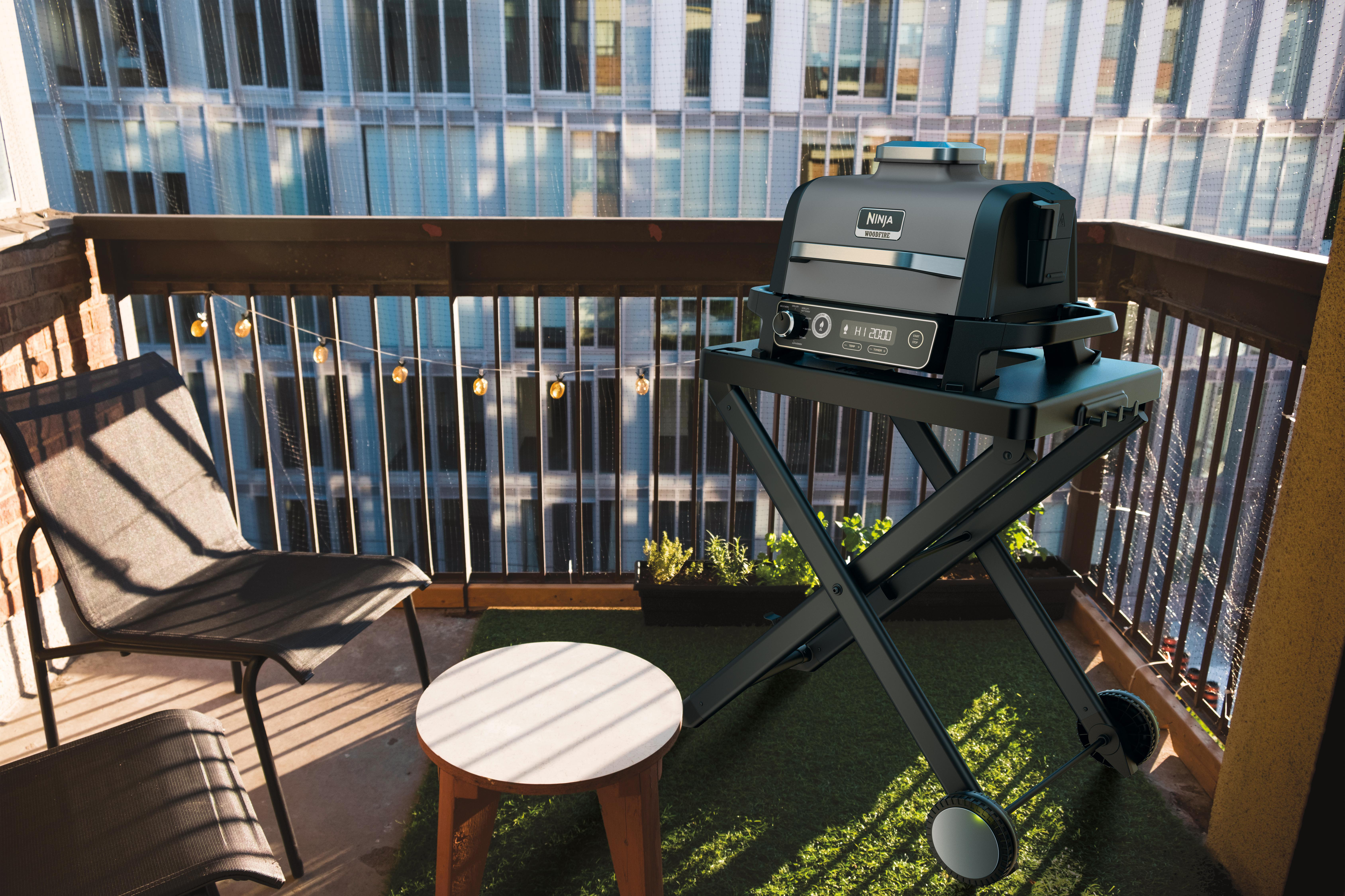 Ninja-Grill auf einem kleinen Balkon mit Stadt im Hintergrund.