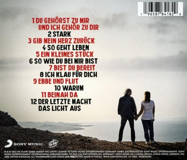 Albumcover mit Titelliste, zwei Hände haltende Personen, Berge und Ozean im Hintergrund.