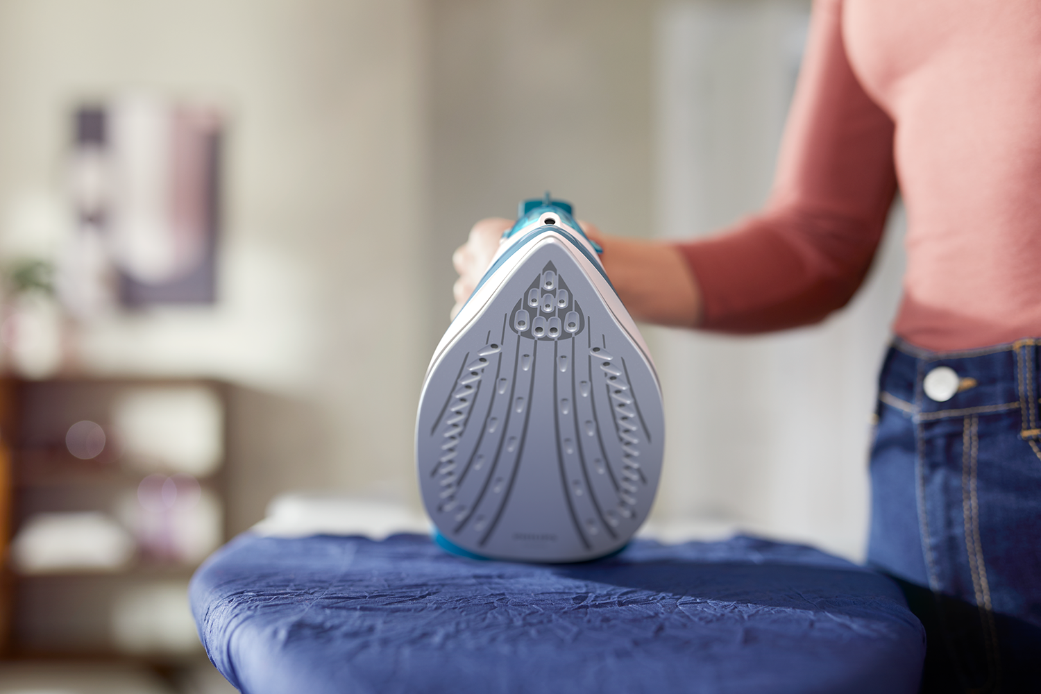 Person ironing clothes on a blue ironing board. Ironing surface is visible.