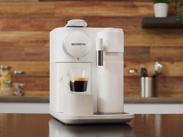 Weiße Nespresso-Maschine mit einem Glas Kaffee.