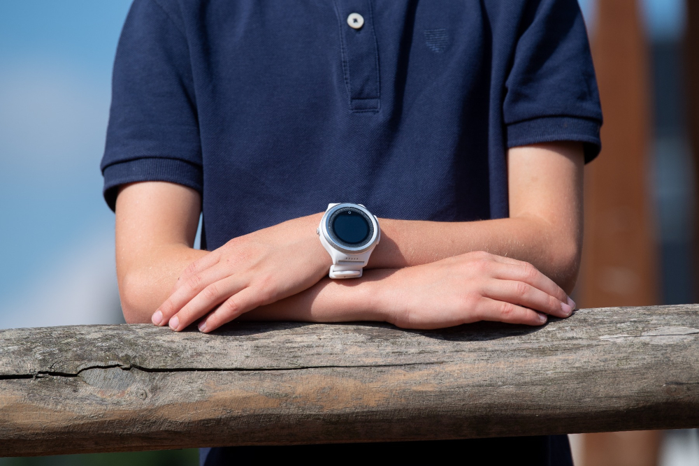 Een pols met een witte smartwatch, armen gekruist.