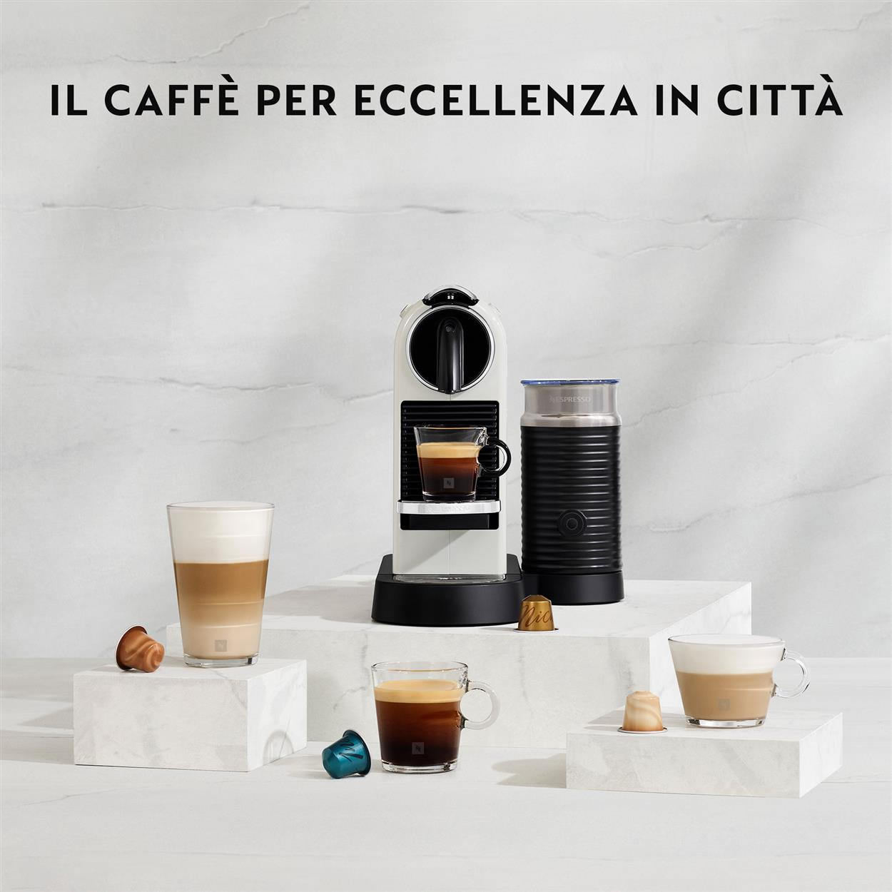 Una macchina per caffè bianca con un bicchiere di caffè e altri articoli per caffè su una superficie bianca.