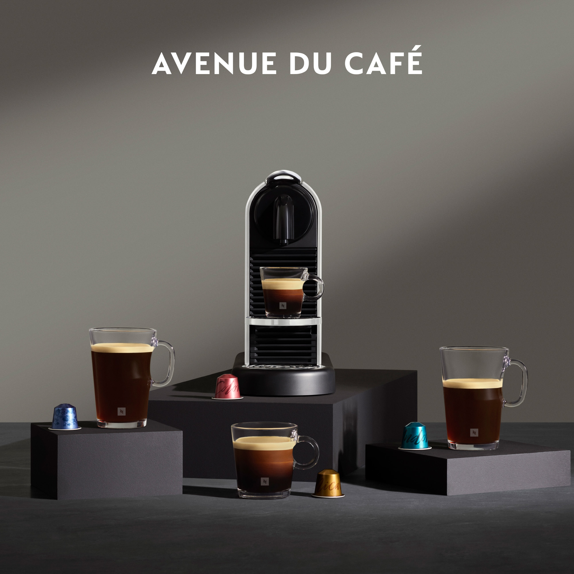 Eine Kaffeemaschine mit mehreren Kaffeetassen und Kapseln auf dunkler Oberfläche.
