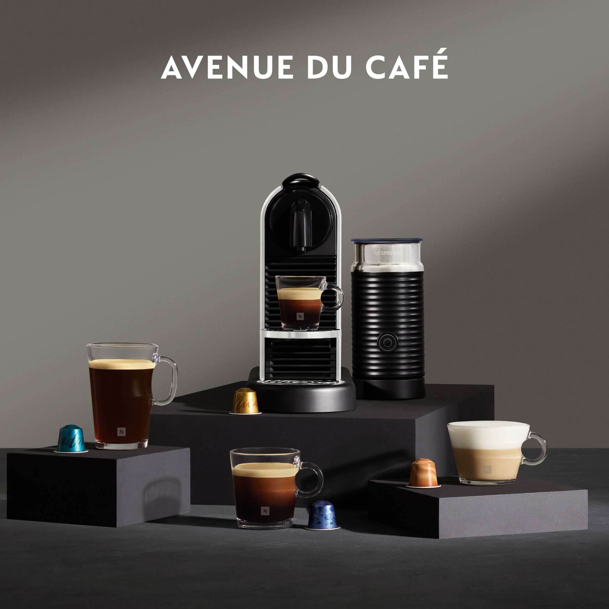 Macchina Nespresso con caffè, tazze e capsule. Il testo "AVENUE DU CAFÉ" è in alto.
