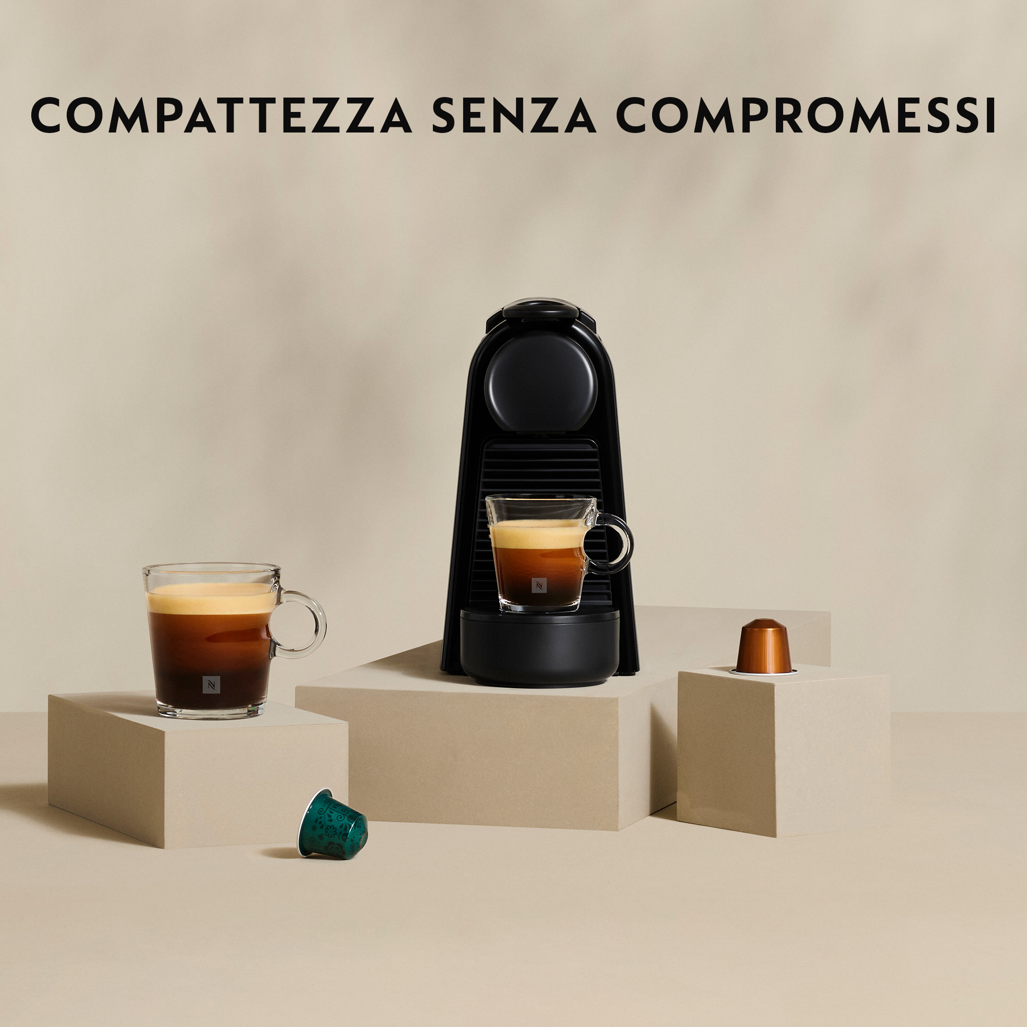 Macchina per caffè espresso nera con due tazze di vetro di caffè. Capsule di caffè laterali. Sfondo beige.