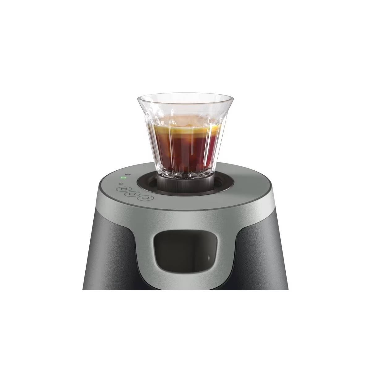 Café que se prepara en un vaso. La máquina está sobre una base oscura. El fondo es blanco.