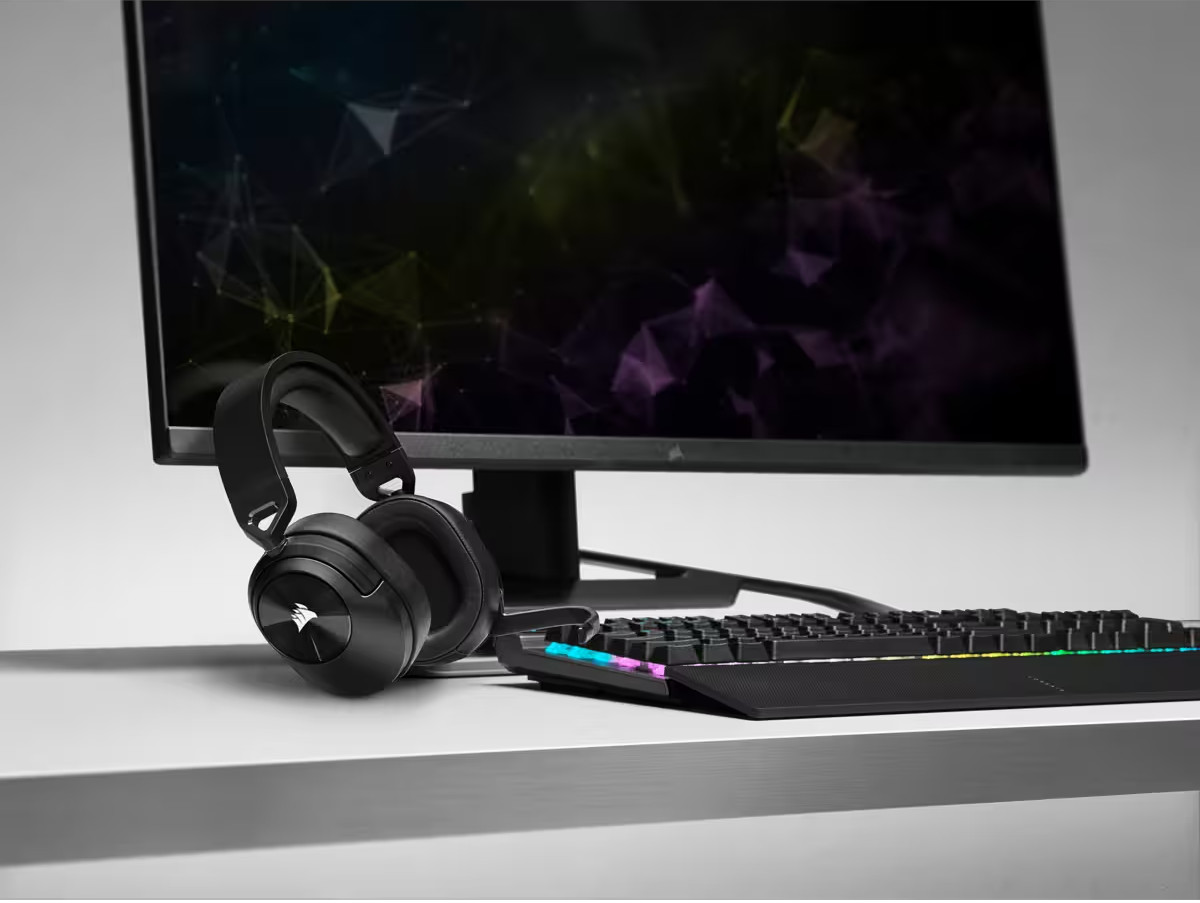 Un casque noir et un clavier sont devant un écran d'ordinateur avec affichage coloré.