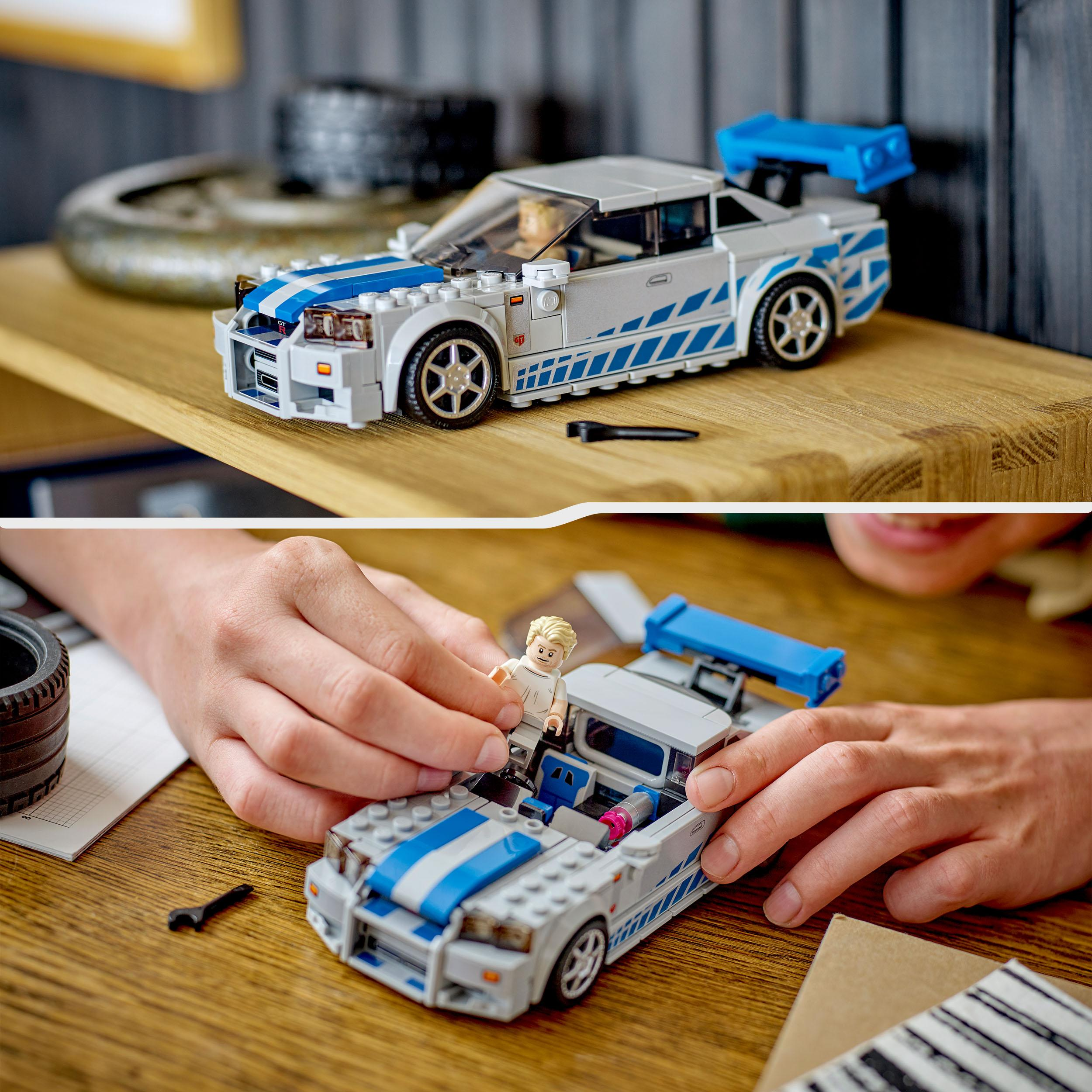 Ein Lego-Auto wird zusammengebaut. Hände bauen ein Auto. Ein Regal ist im Hintergrund.