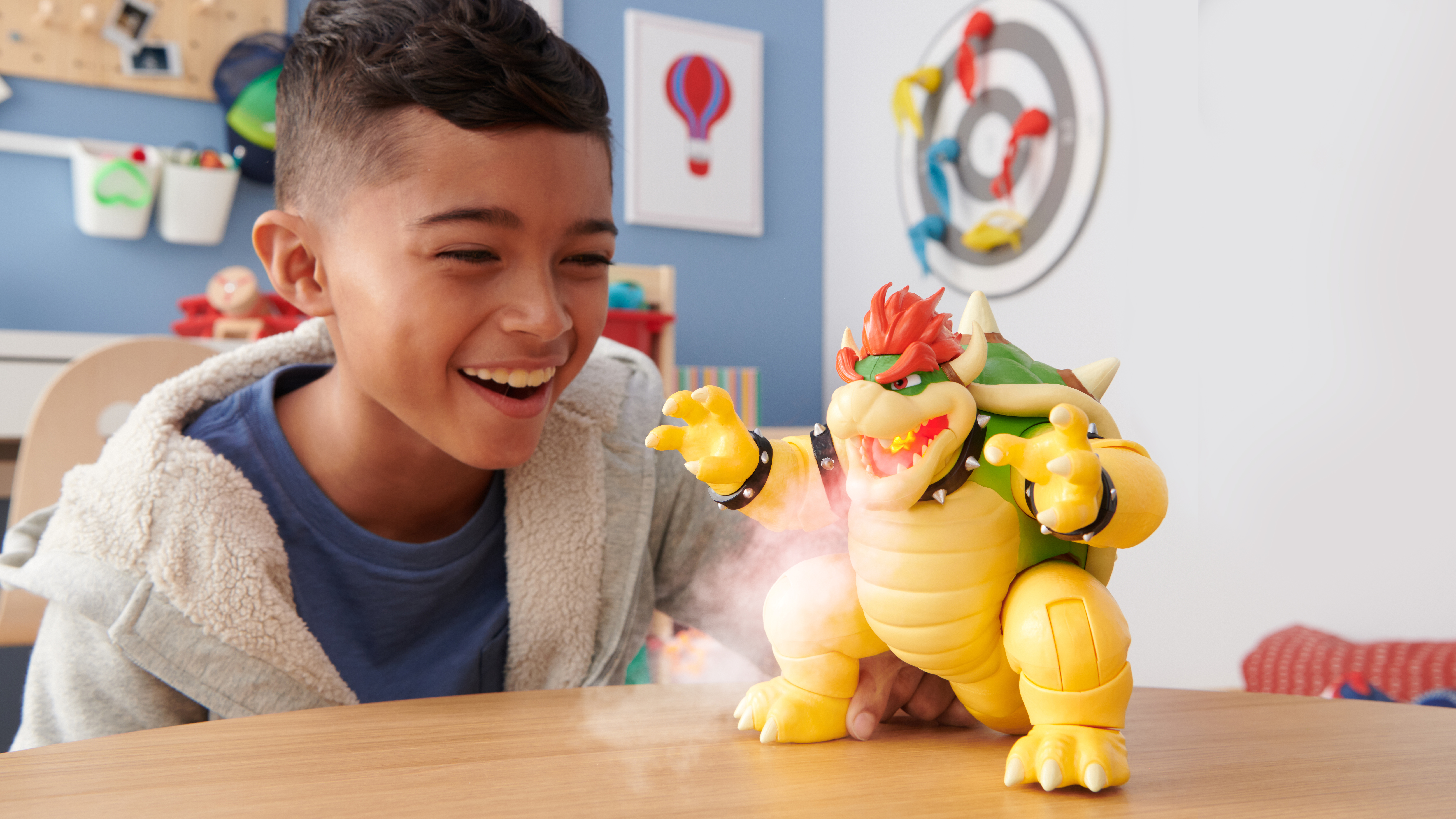 Junge hält und interagiert mit einem Bowser-Spielzeug, mit lächelndem Gesicht.