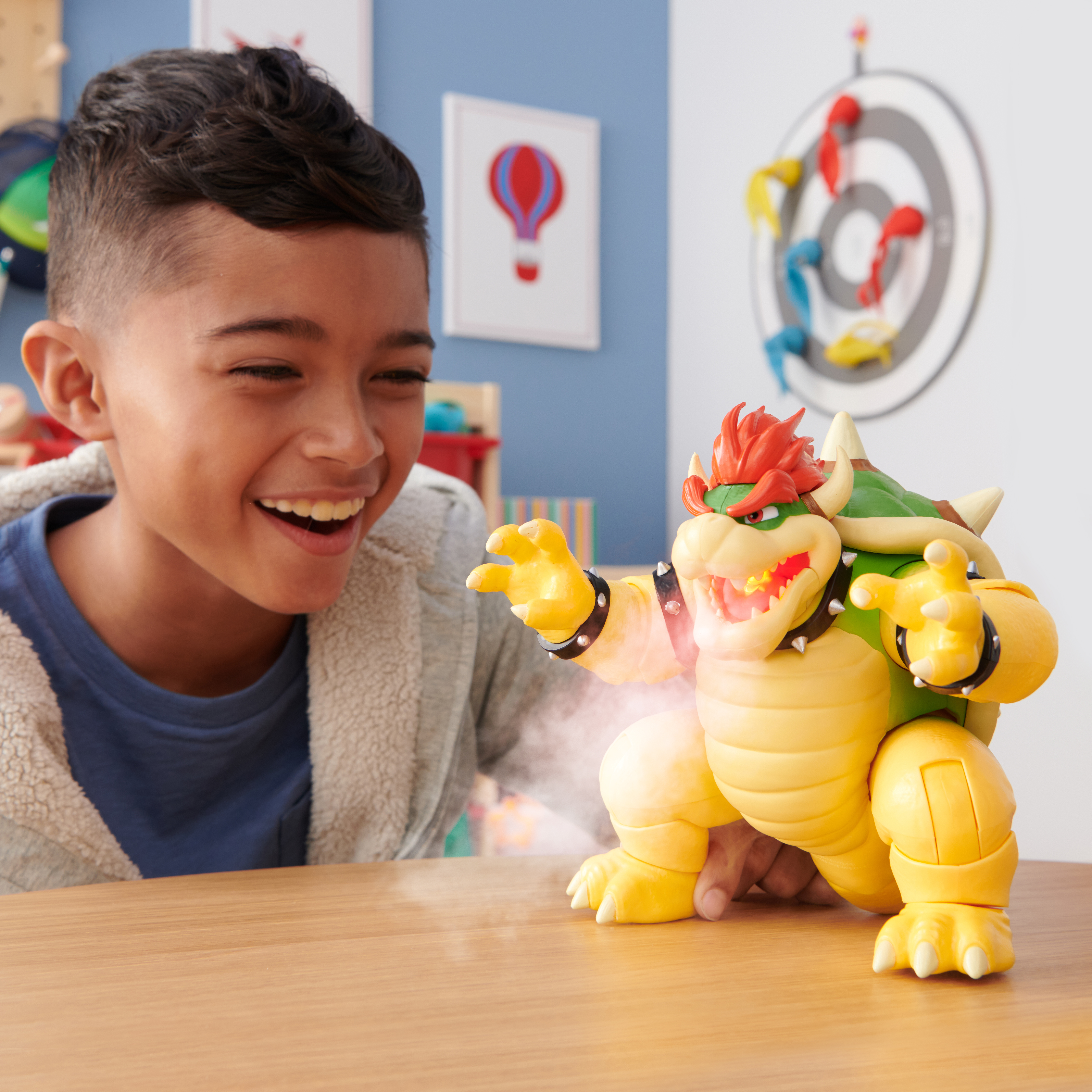 Ein lächelnder Junge schaut sich eine Bowser-Spielzeugfigur an. Das Spielzeug hat einen gelben Körper und rote Haare.