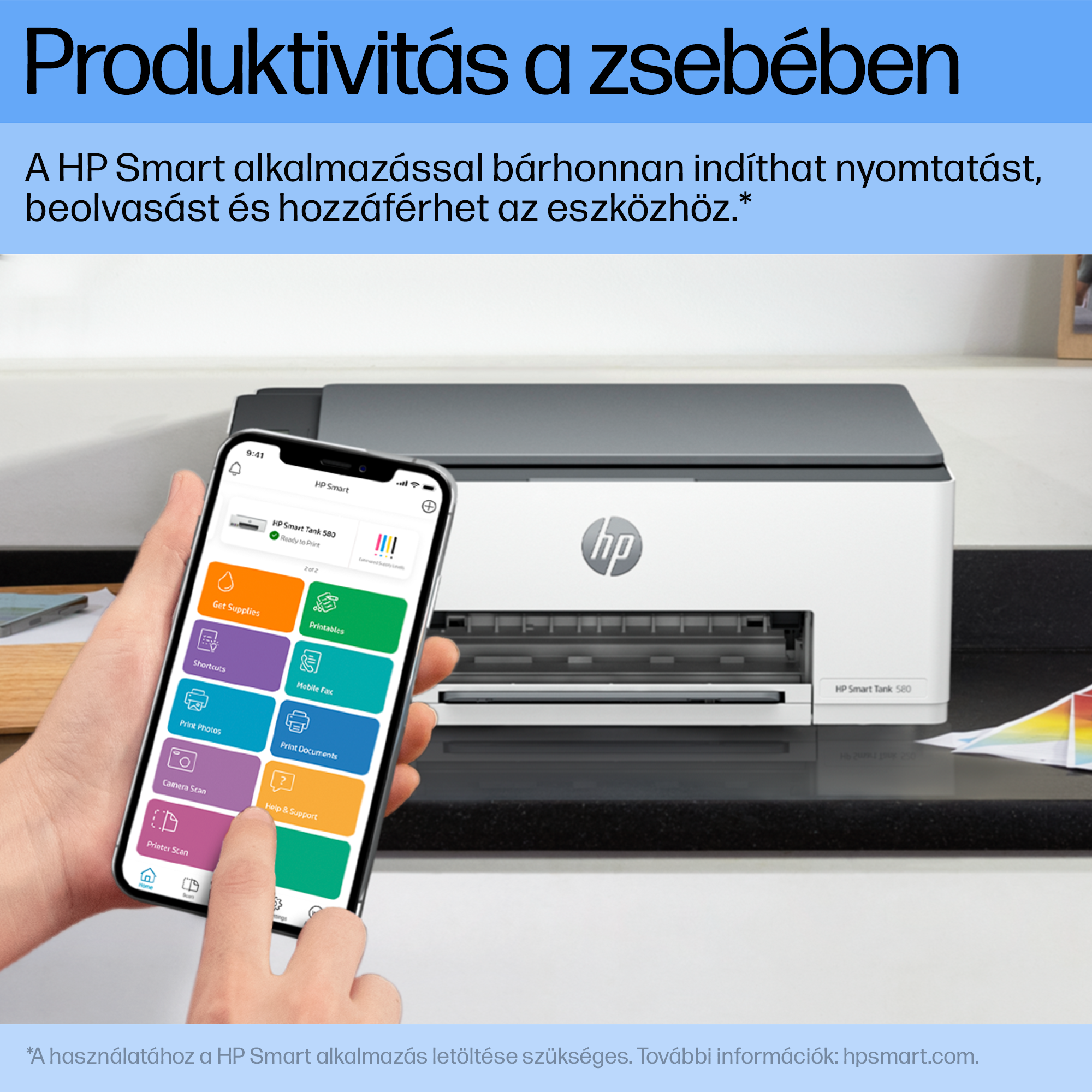 Egy kéz okostelefont, nyomtatót és egyéb tárgyakat tart a háttérben.