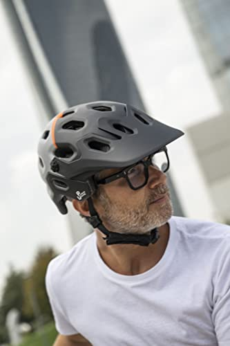 Man met helm en bril die omhoog kijkt, met een vage stad op de achtergrond.