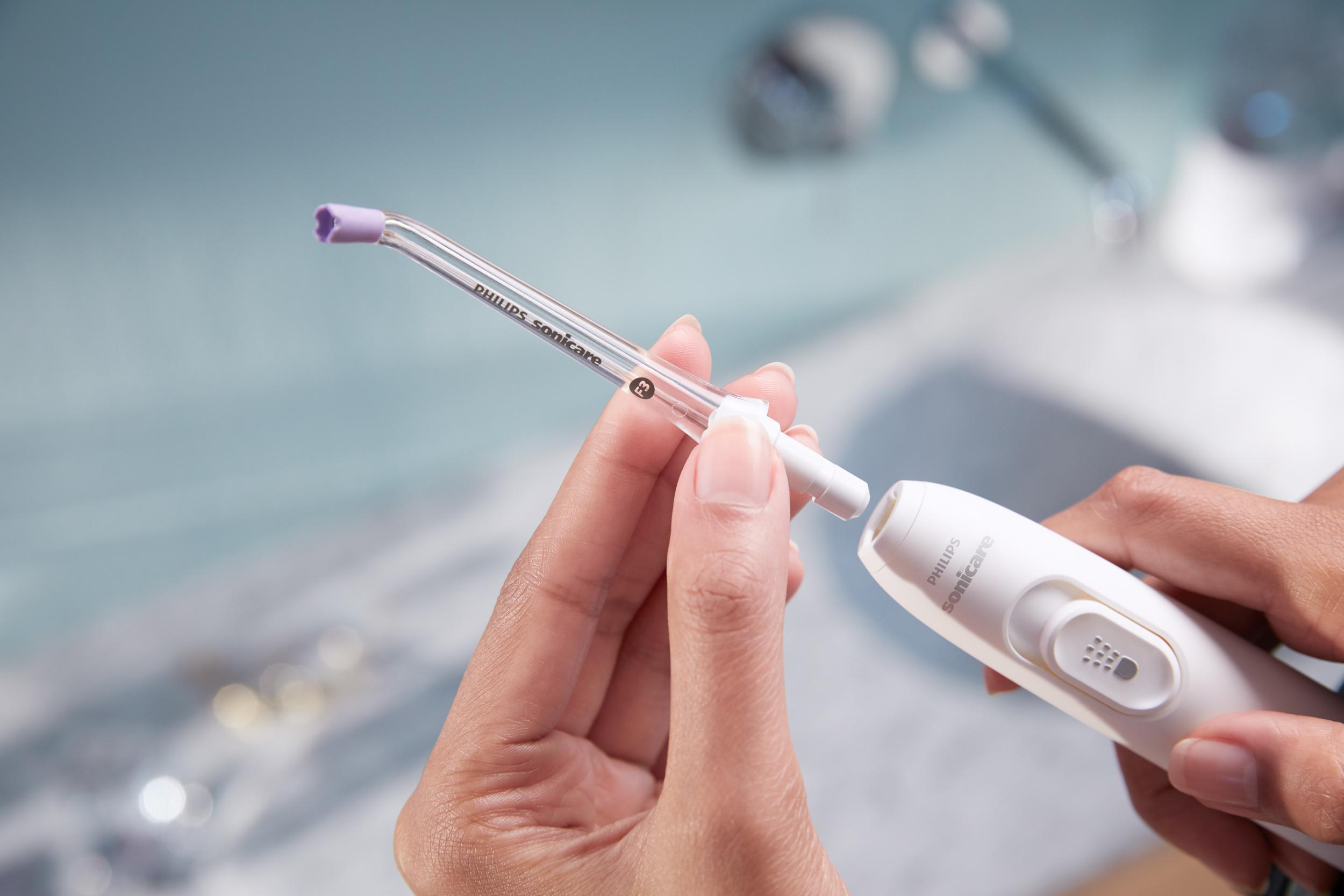 Die Hände einer Person halten einen Philips Sonicare Wasserflosserkopf.