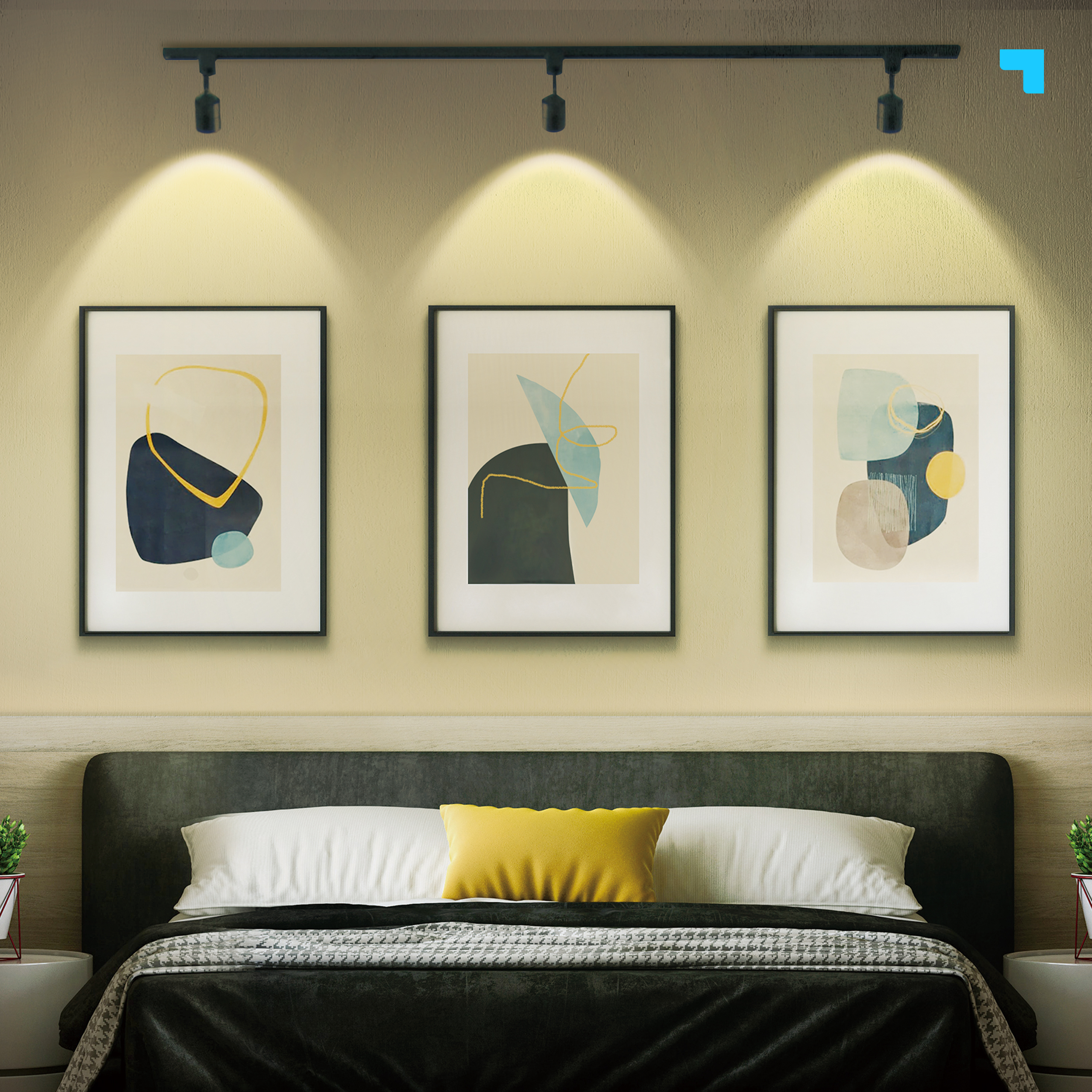 Tres piezas de arte abstracto enmarcadas sobre una cama. El arte tiene formas beige y azules. Las luces brillan sobre el arte.