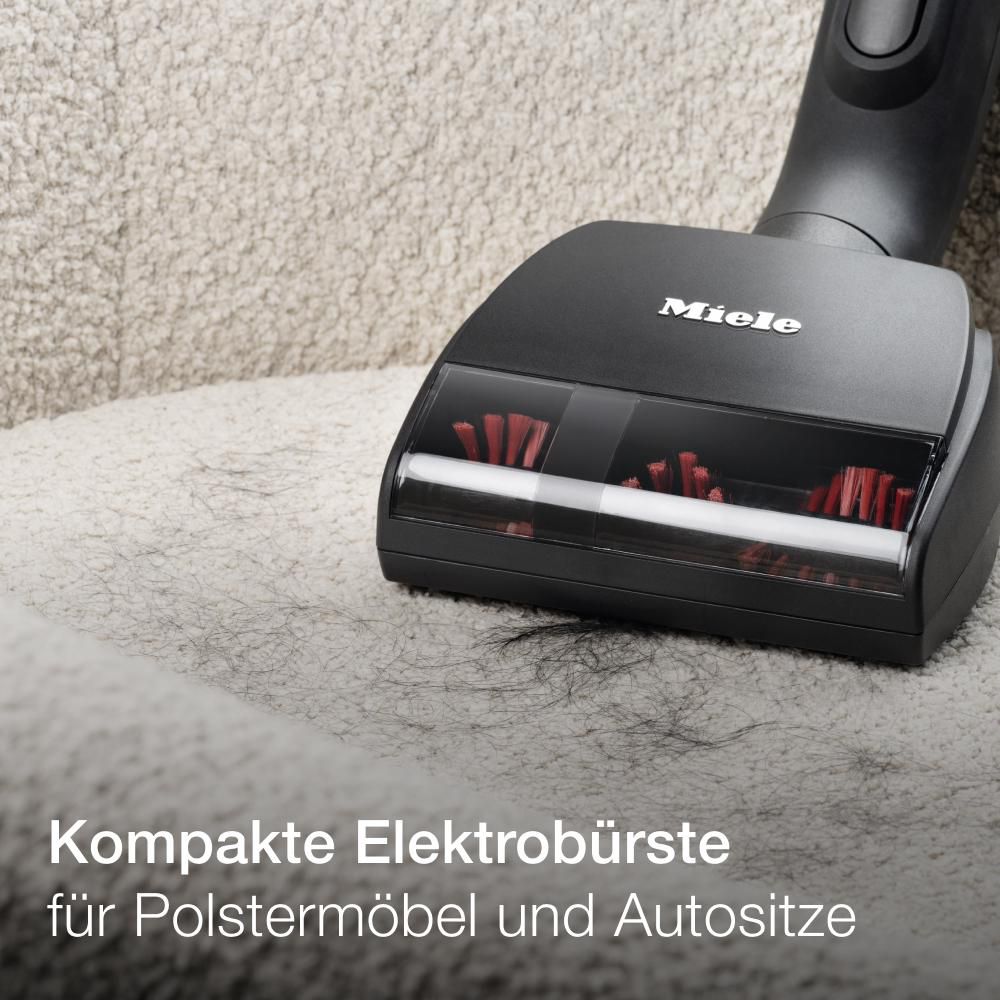 Ein Miele-Staubsaugerkopf reinigt ein Sofa. Die Bürste ist nah an der Oberfläche.