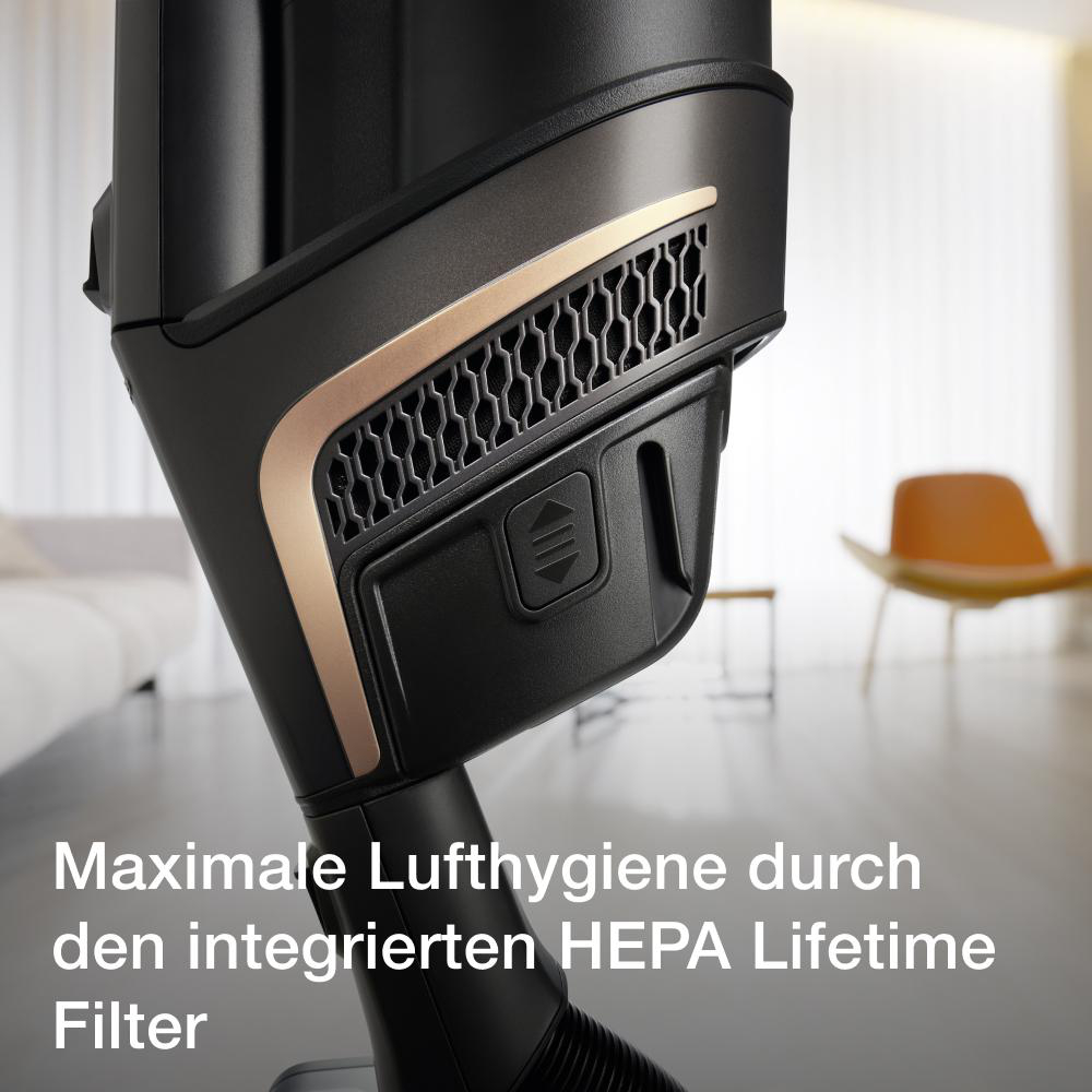 Nahaufnahme eines Staubsaugers mit schwarzen und goldenen Details. Der Hintergrund ist unscharf.